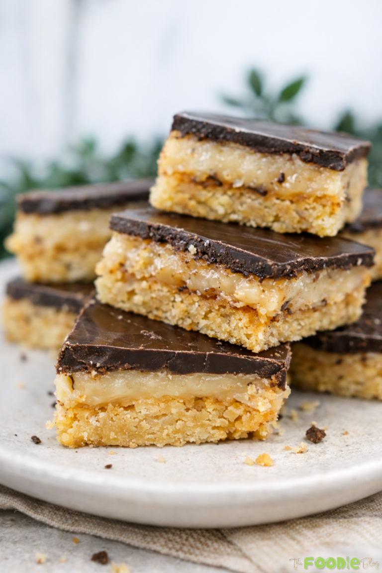 Close-up of caramel slice bars with a thick caramel layer and smooth chocolate topping on a plate.