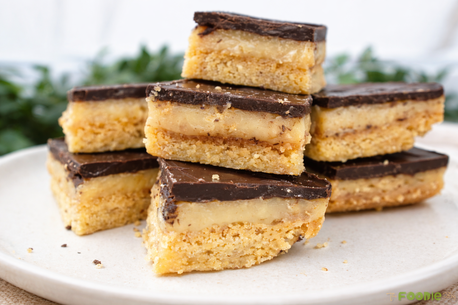 Stacked caramel slice squares showing a buttery base, creamy caramel filling, and chocolate top layer.