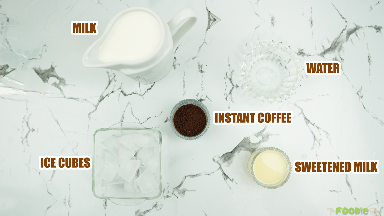 Overhead view of milk, water, instant coffee, ice cubes, and sweetened milk for making chilled coffee
