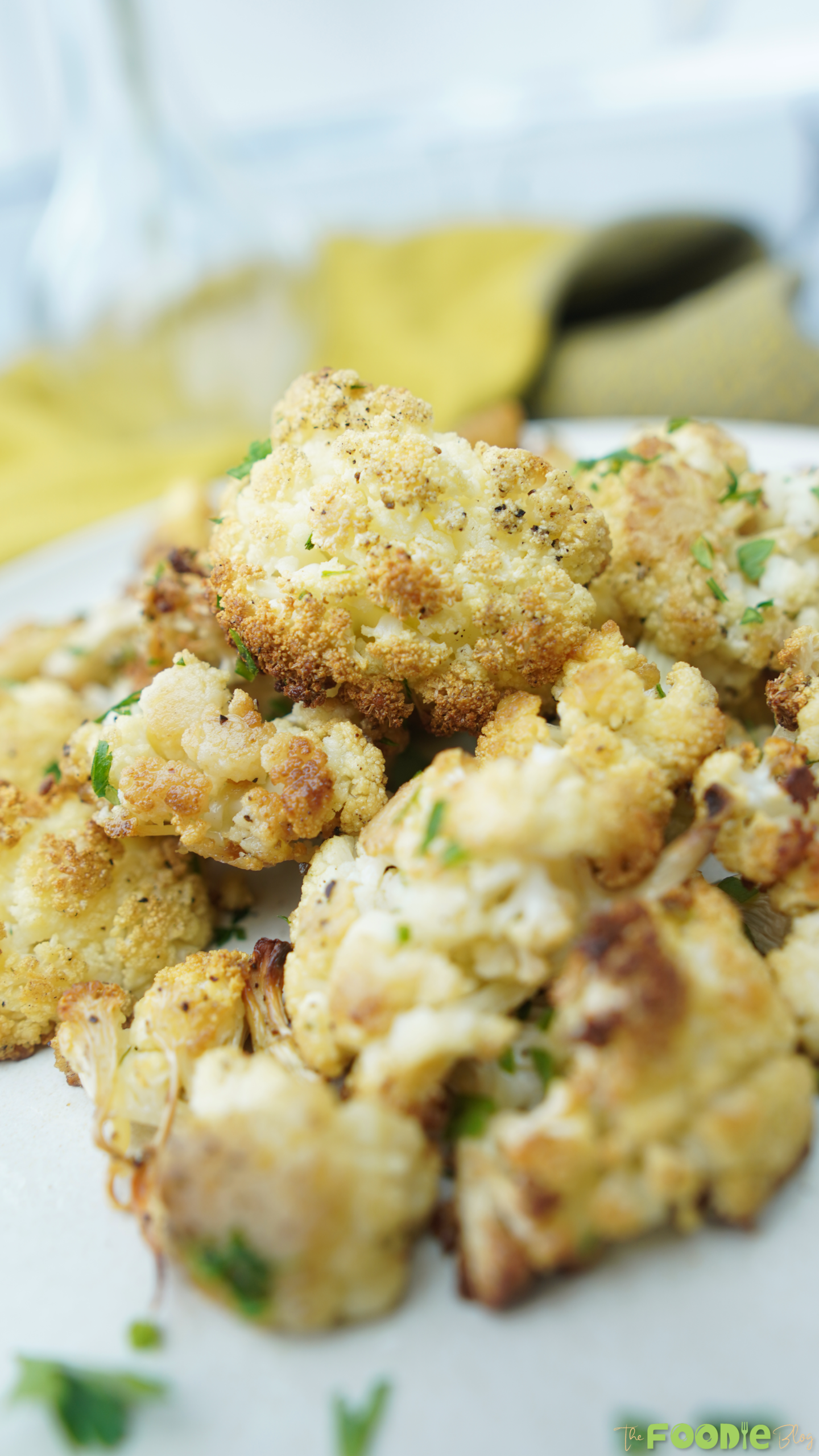 Close-up of golden roasted cauliflower florets with specks of black pepper and herbs