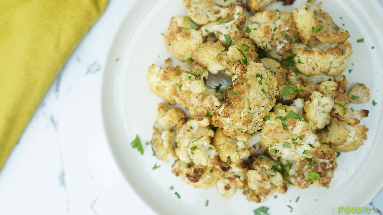 Top-down view of roasted cauliflower florets with browned edges and chopped parsley