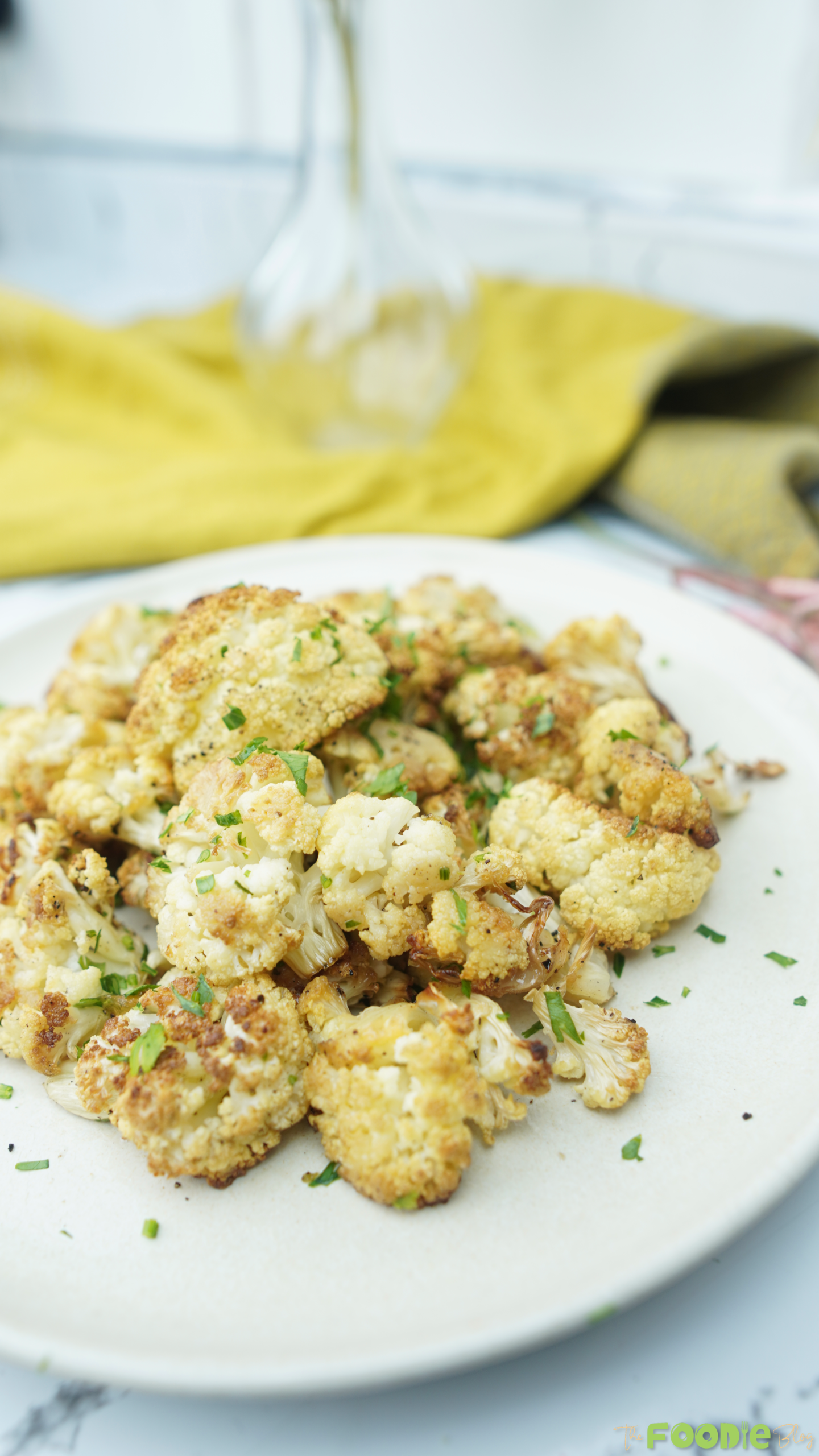 t: Roasted cauliflower florets on a white plate, golden and sprinkled with herbs