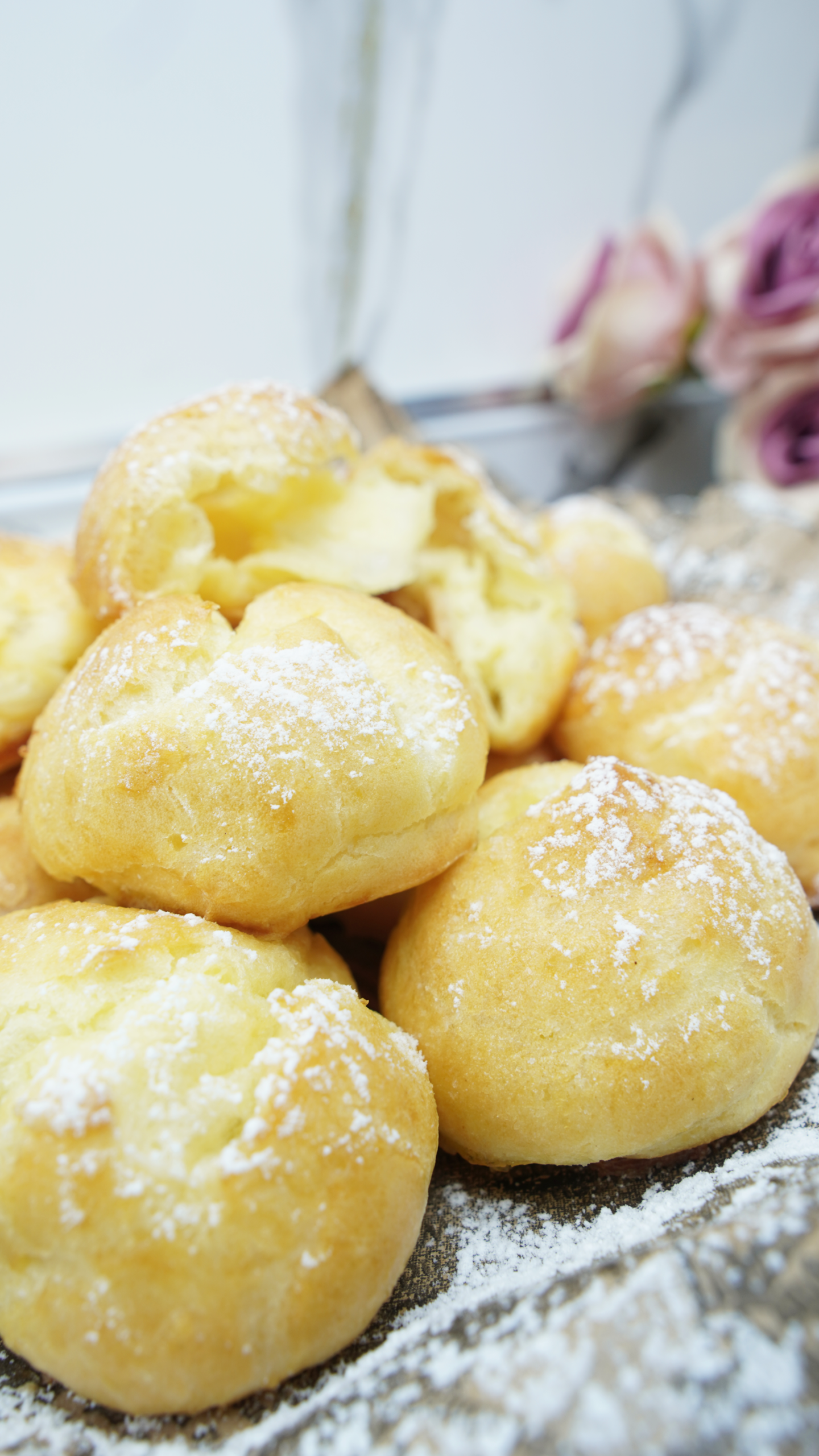 Golden choux pastry puffs dusted with powdered sugar on a tray