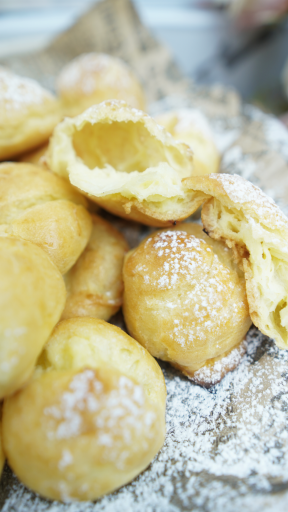 Close-up of classic choux pastry puffs dusted with powdered sugar, showing the light hollow inside