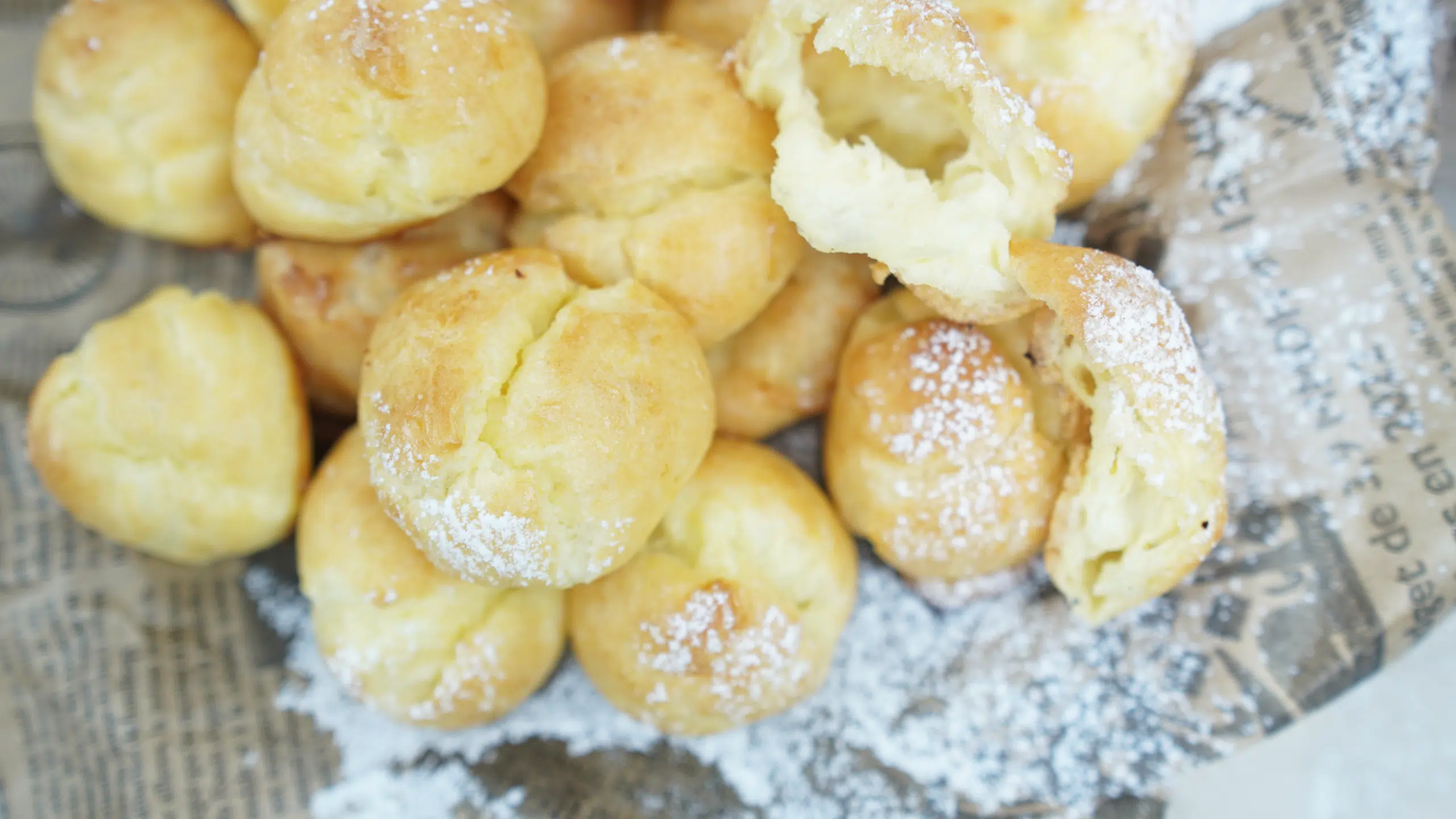 Overhead view of classic choux pastry puffs sprinkled with powdered sugar on a rustic surface