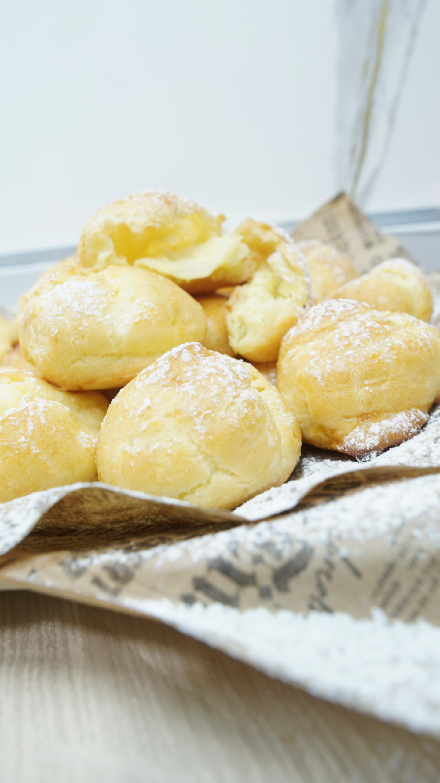 Classic choux pastry puffs dusted with powdered sugar arranged on paper-lined serving board