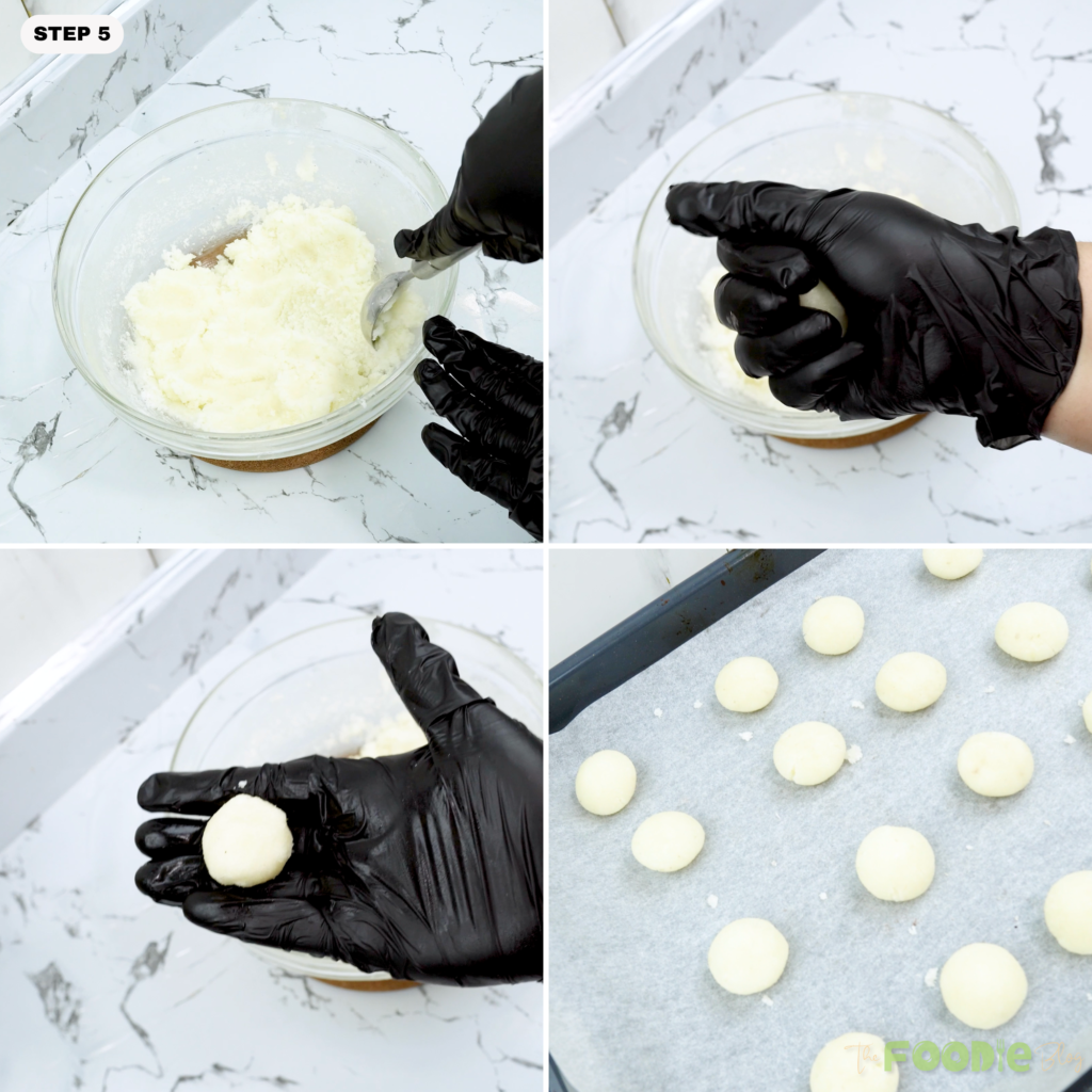 Hands shaping coconut macaroon dough into round balls on a lined tray