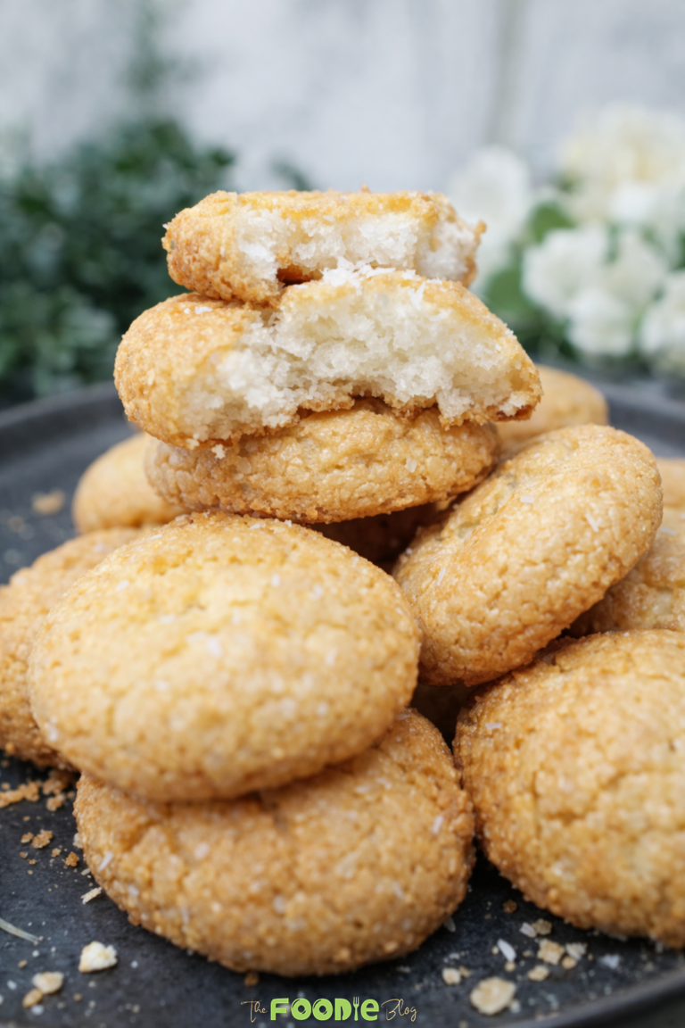 Stacked coconut macaroons with a soft chewy center and lightly golden edges on a dark plate.