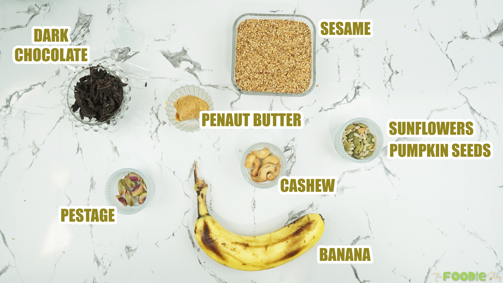 Overhead view of banana, sesame seeds, chocolate, peanut butter, and toppings for the recipe