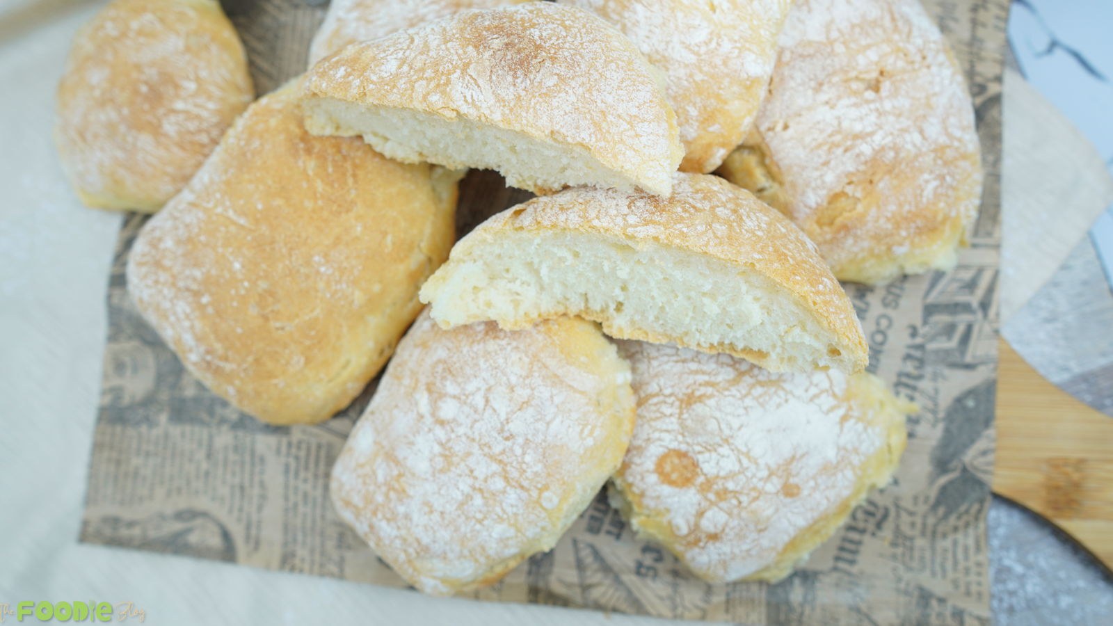 Cut homemade ciabatta rolls showing an airy crumb on a serving board