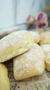 Close-up of flour-dusted homemade ciabatta rolls stacked on a board