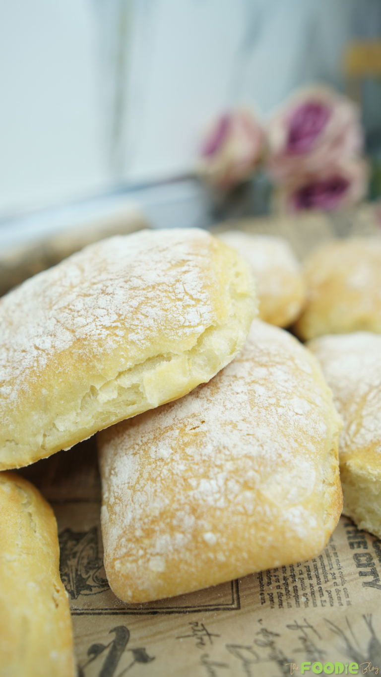 Close-up of flour-dusted homemade ciabatta rolls stacked on a board