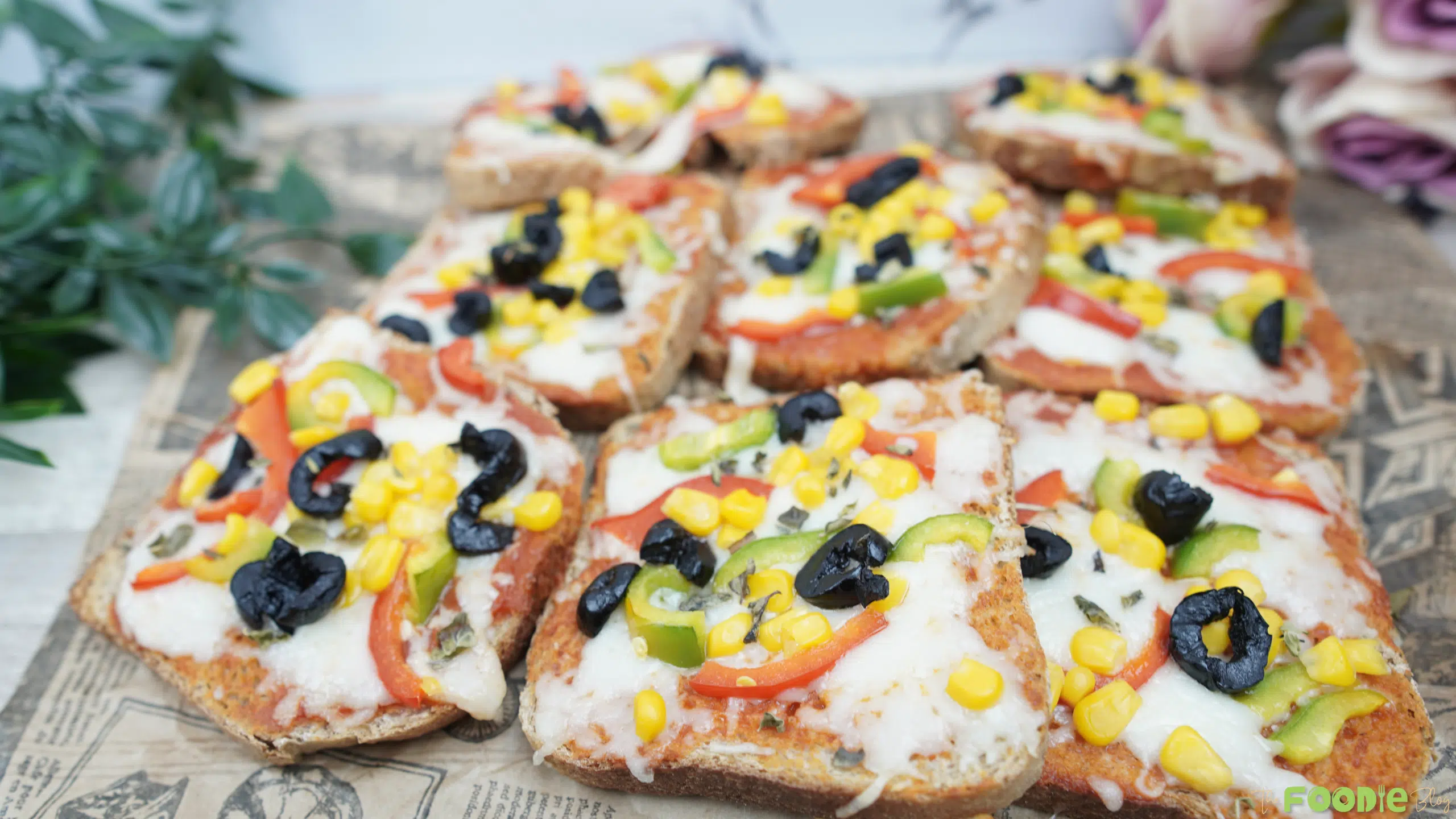 Tray of EASY PIZZA TOAST topped with melted mozzarella, corn, bell peppers, and black olives