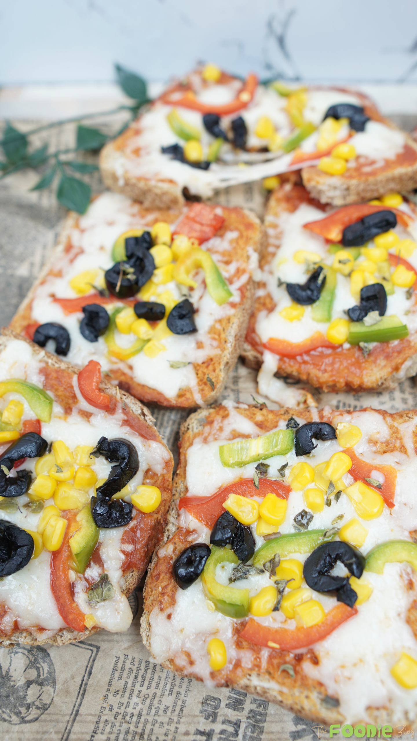 Overhead view of several EASY PIZZA TOAST slices topped with mozzarella, corn, peppers, and olives
