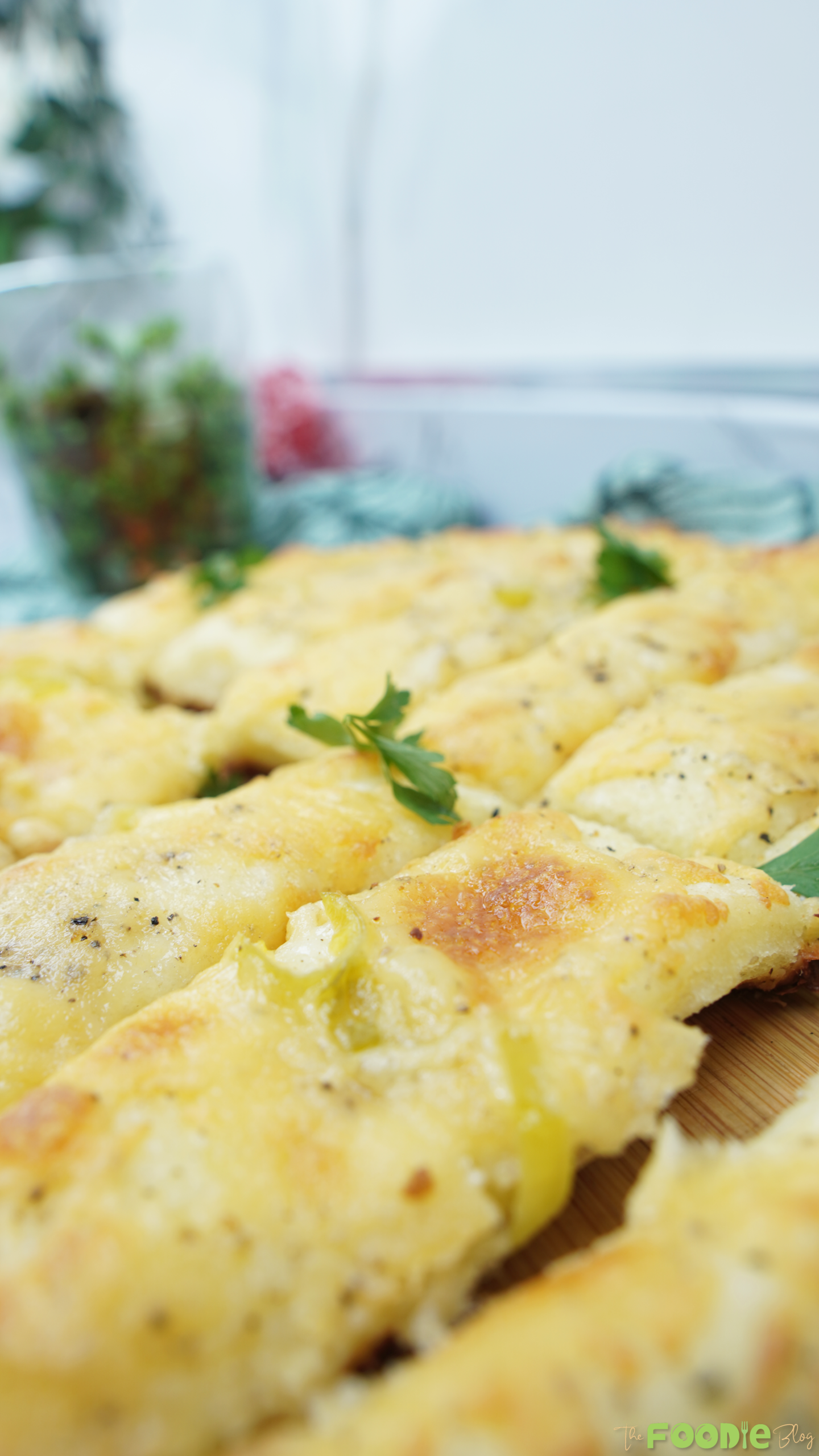 Golden cheesy garlic bread sticks on a wooden board with parsley
