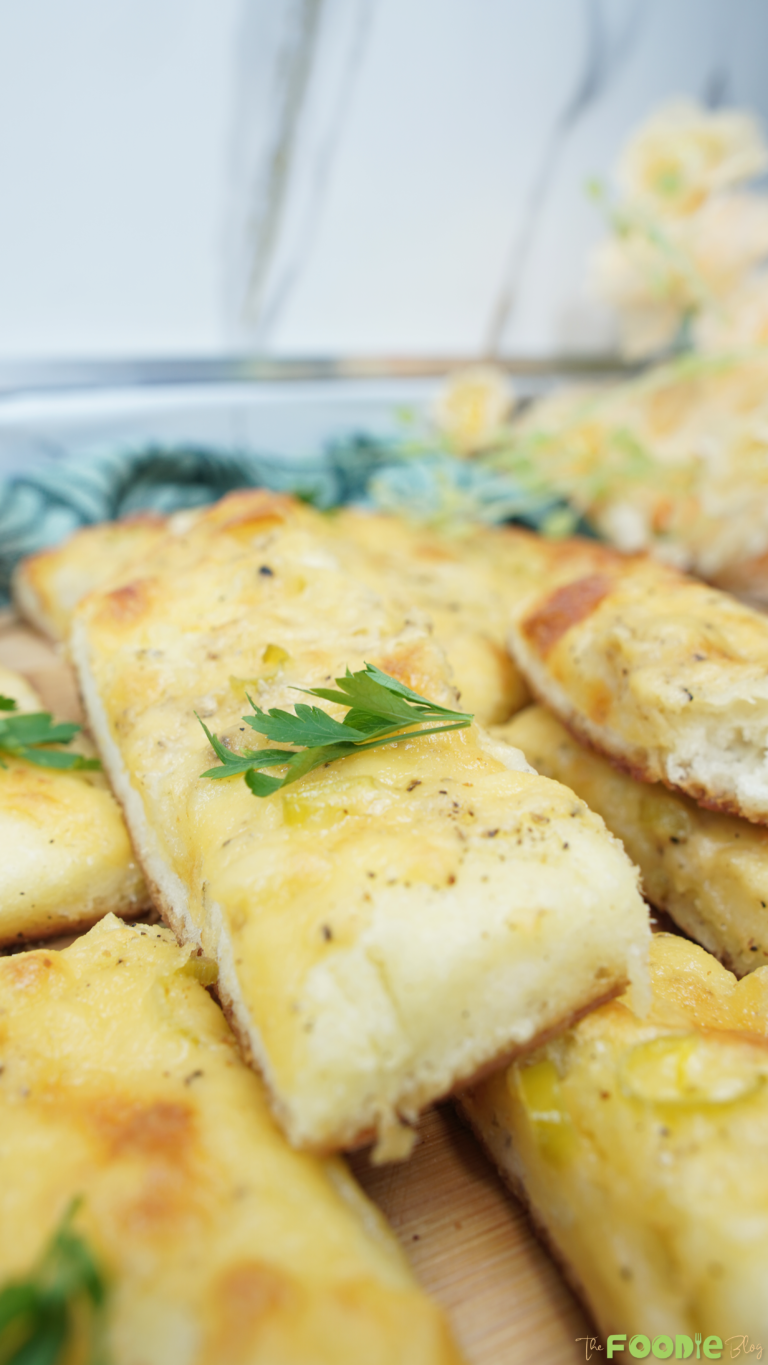 Close-up of a cheesy garlic bread stick with parsley on top