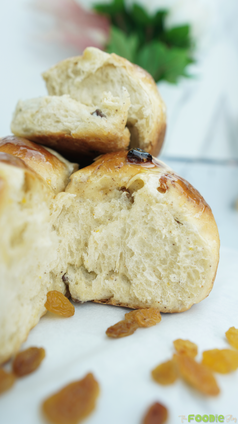Close-up of a torn spiced bun showing fluffy interior with raisins and a soft crumb