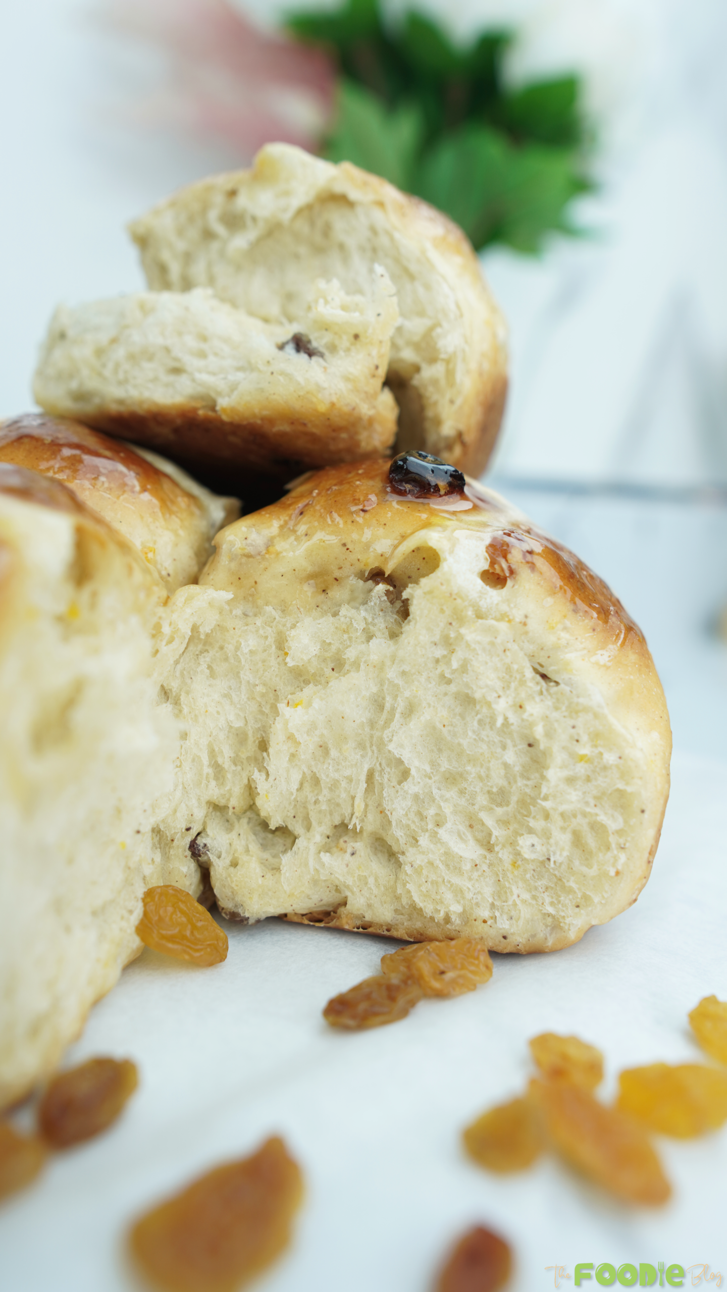 Close-up of a torn spiced bun showing fluffy interior with raisins and a soft crumb