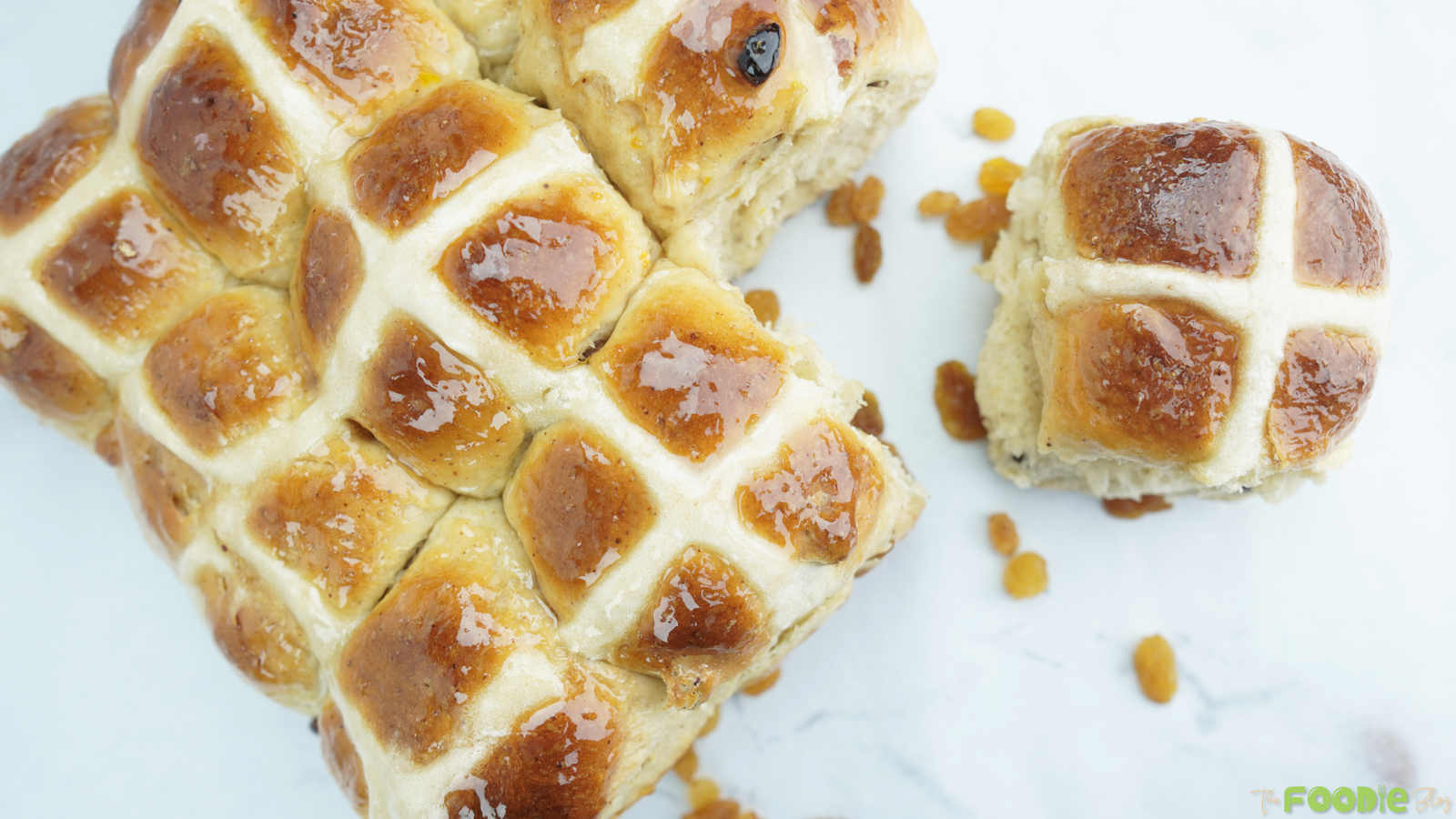 Top view of glazed hot cross buns with classic white crosses and scattered sultanas