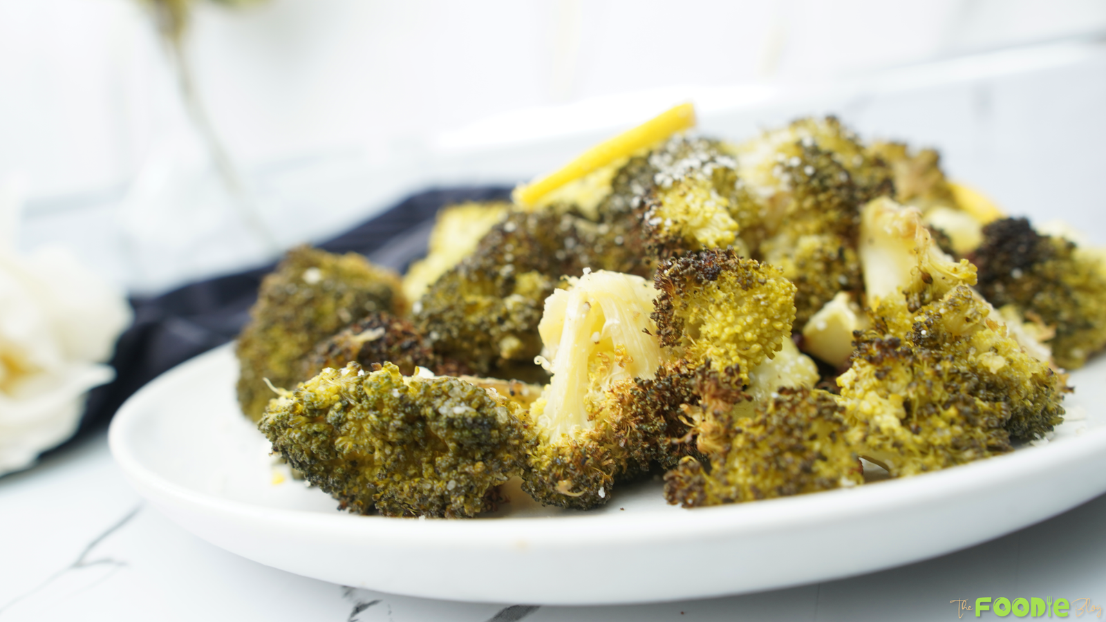 Roasted broccoli on a white plate with browned edges and lemon