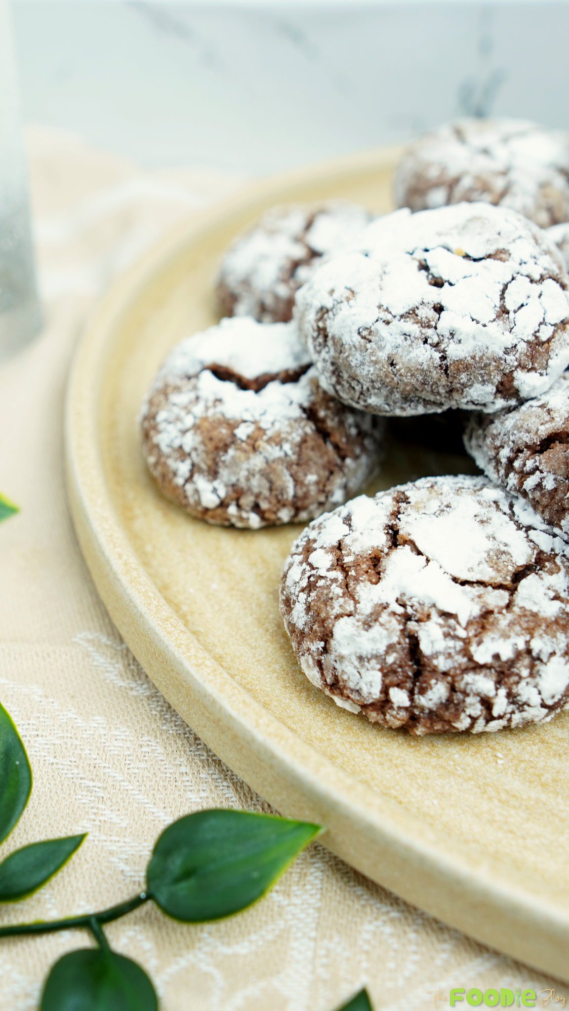 Close-up of powdered sugar–coated cocoa crinkle cookies on a ceramic plate