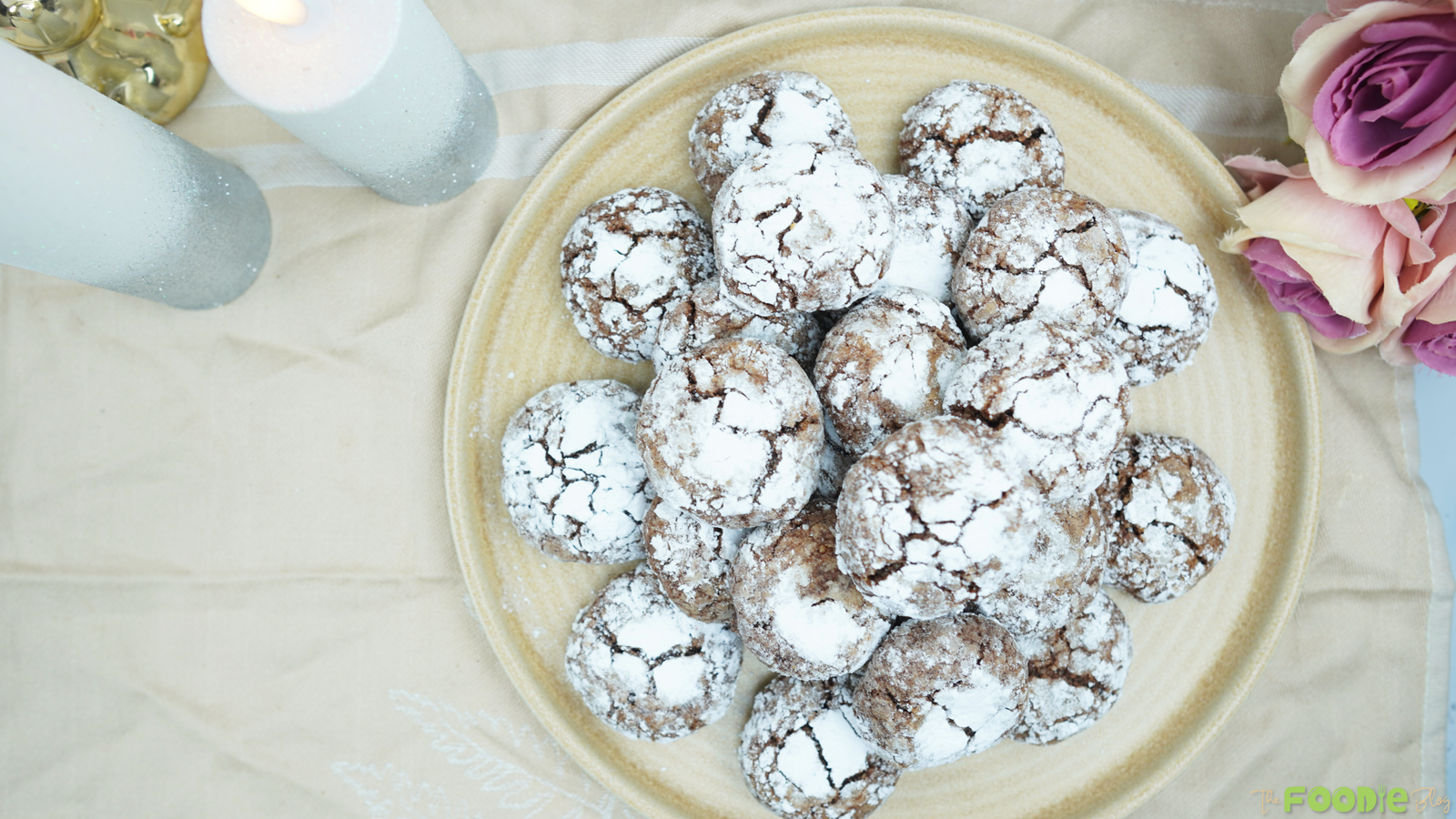 Overhead plate of powdered sugar–coated cocoa cookies with crackly tops