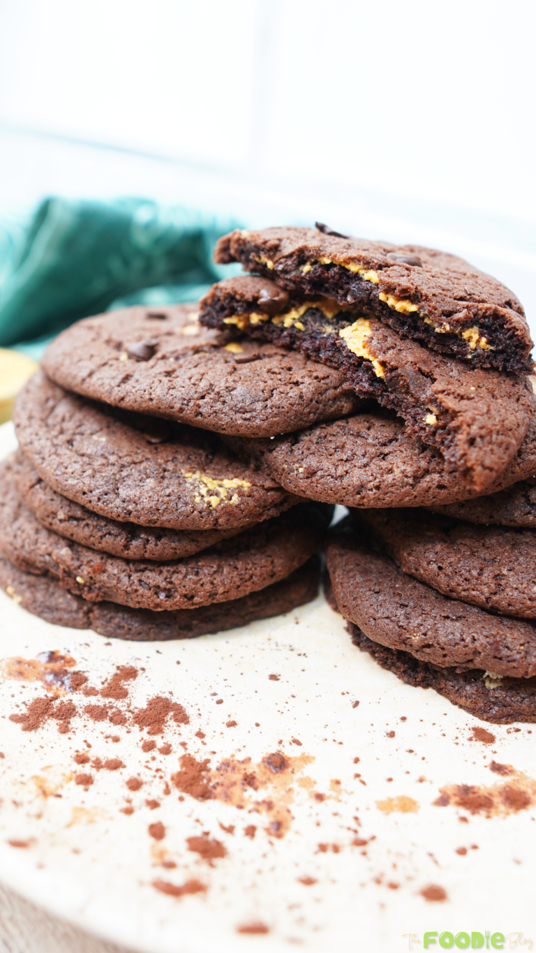 Chocolate peanut butter cookies stacked with a broken cookie showing the peanut butter layer inside