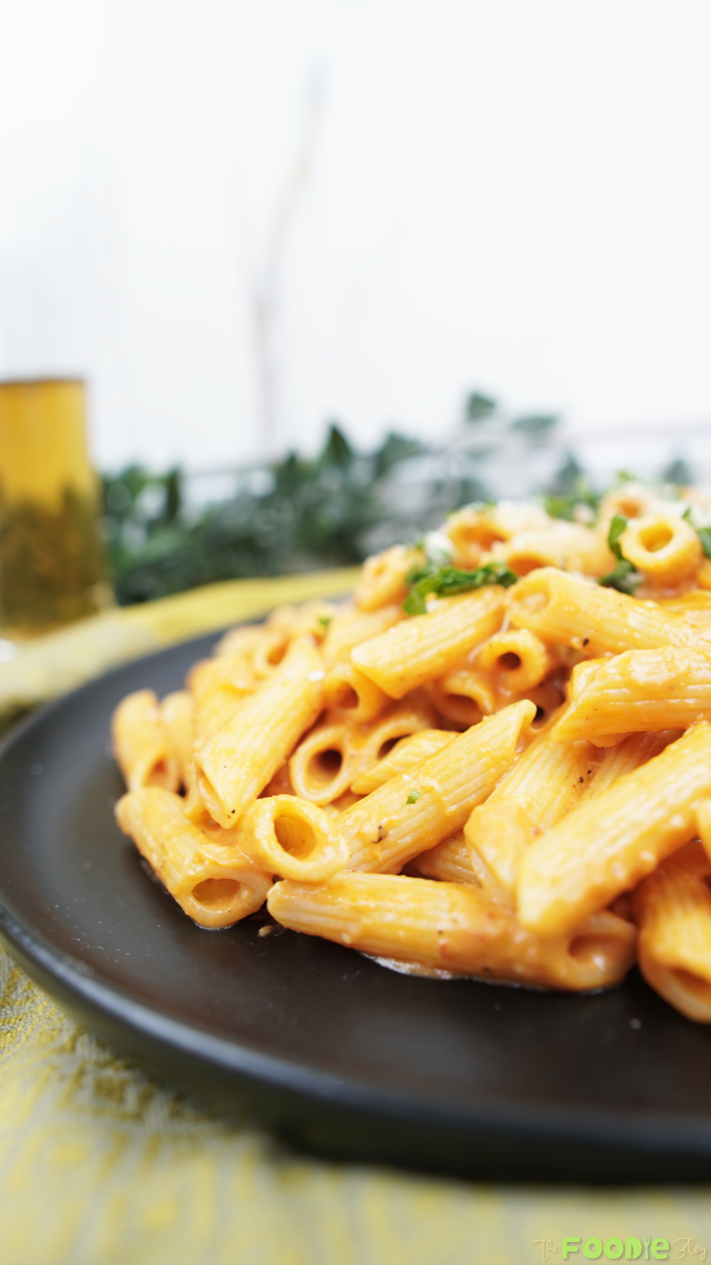 Close-up of penne alla vodka coated in creamy pink vodka sauce, served on a black plate with parsley and parmesan.