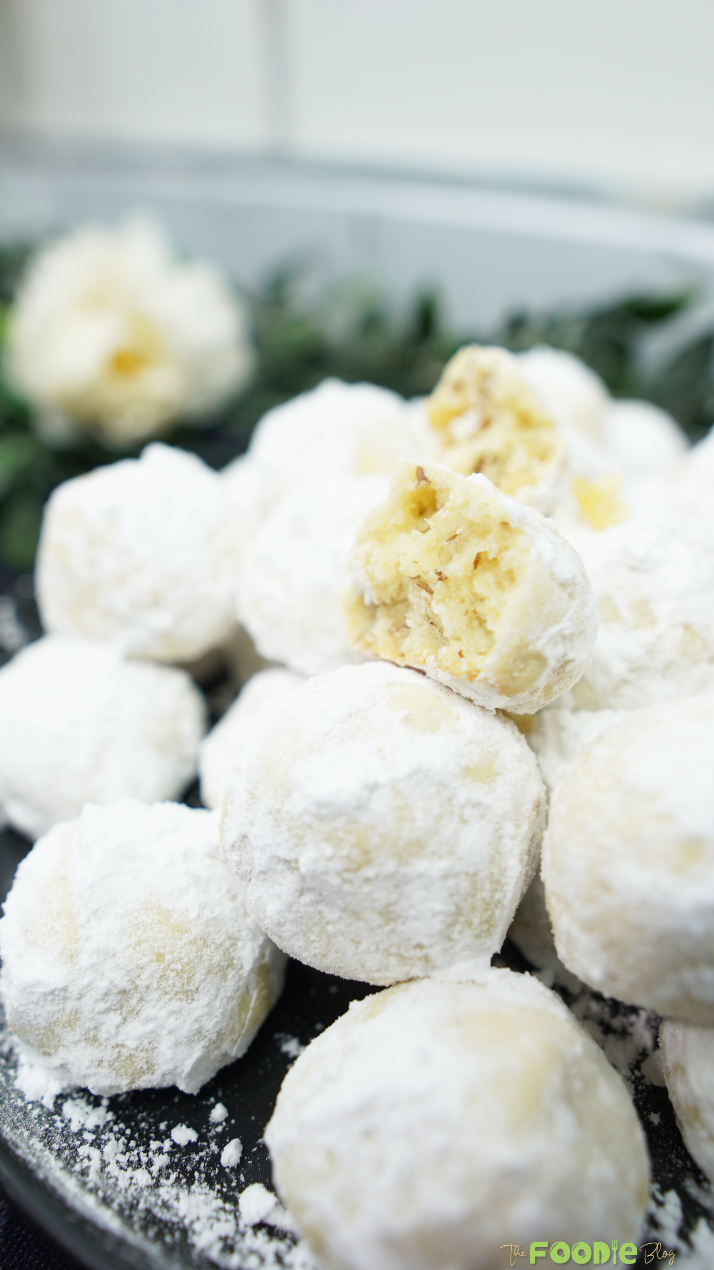 Close-up of snowball cookies coated in powdered sugar with one cookie broken open showing walnut pieces
