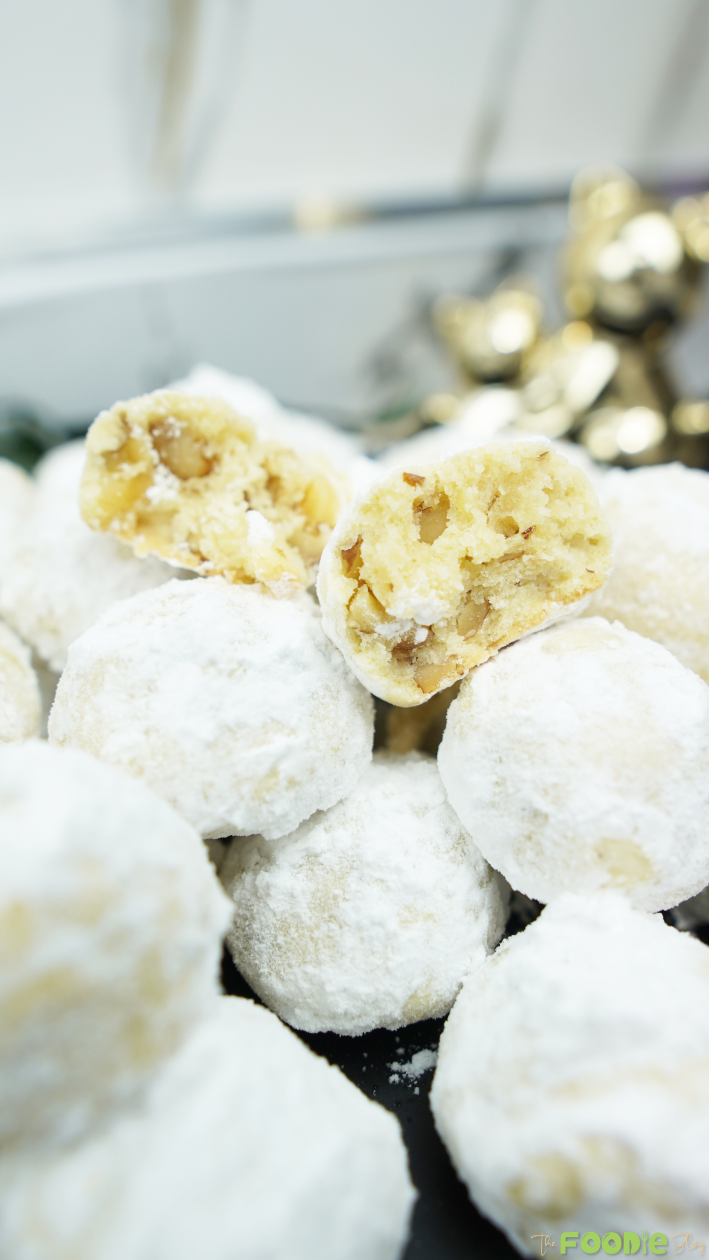 : Close-up of powdered sugar snowball cookies with a broken cookie showing walnut pieces