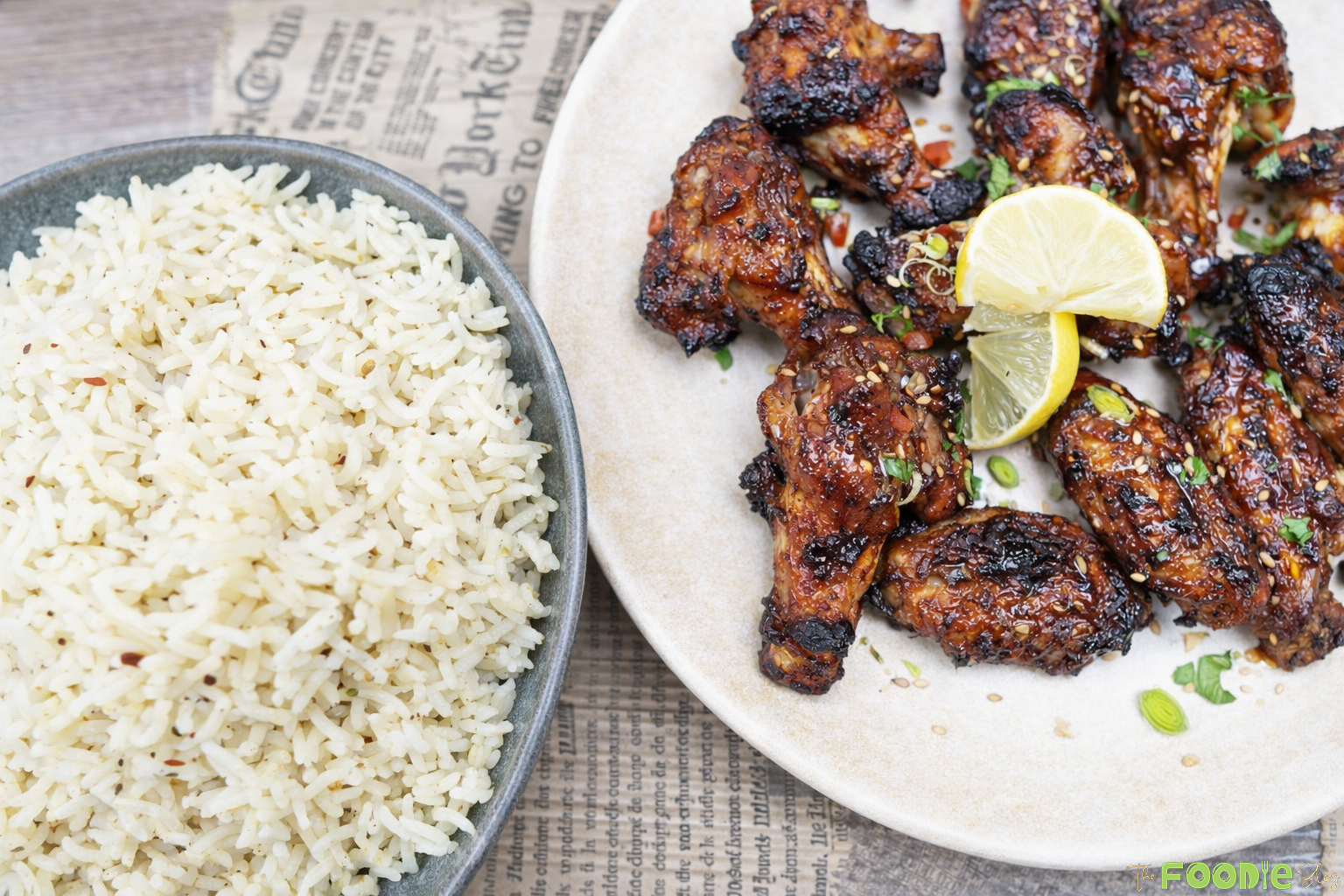Sticky Chinese chicken wings served with seasoned rice, topped with sesame seeds and fresh herbs.