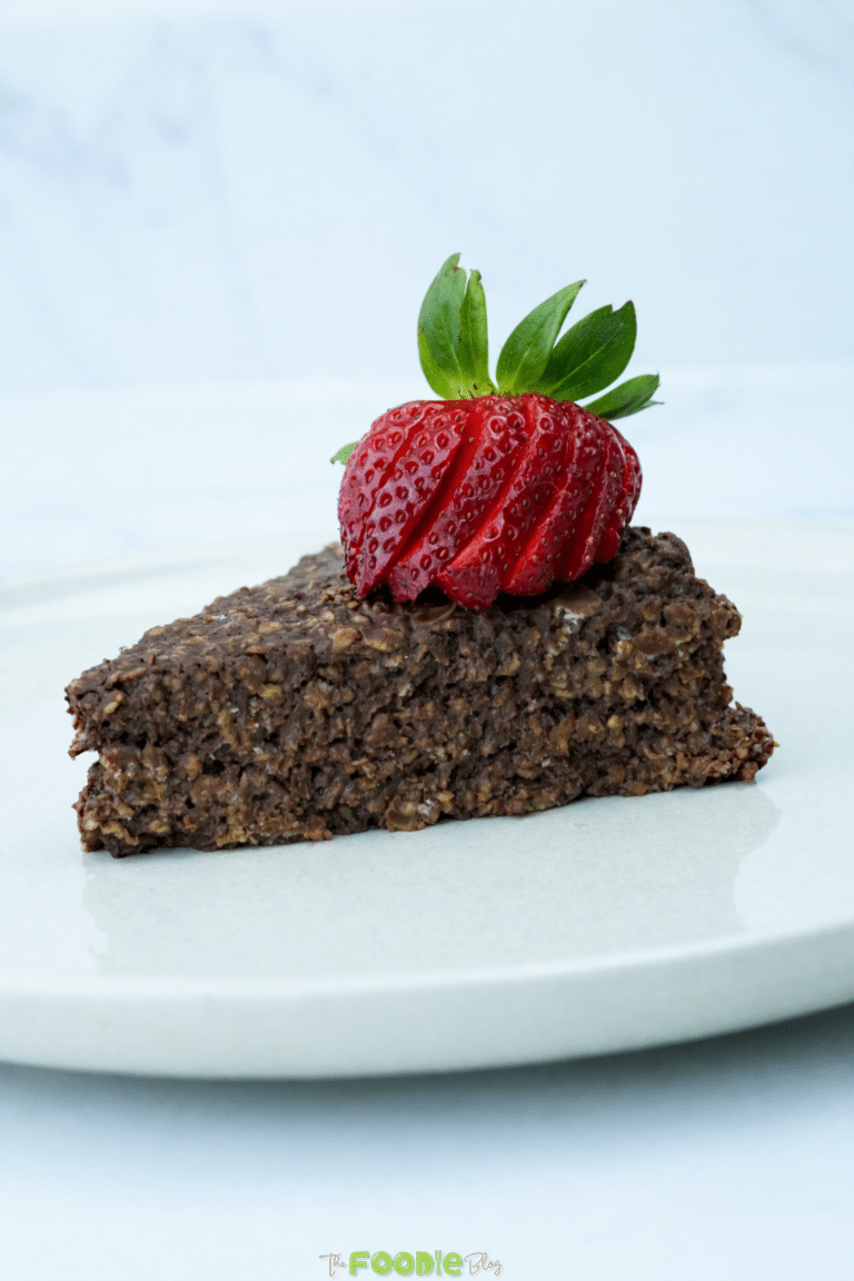 Single slice of chocolate oatmeal cake on a plate topped with a strawberry