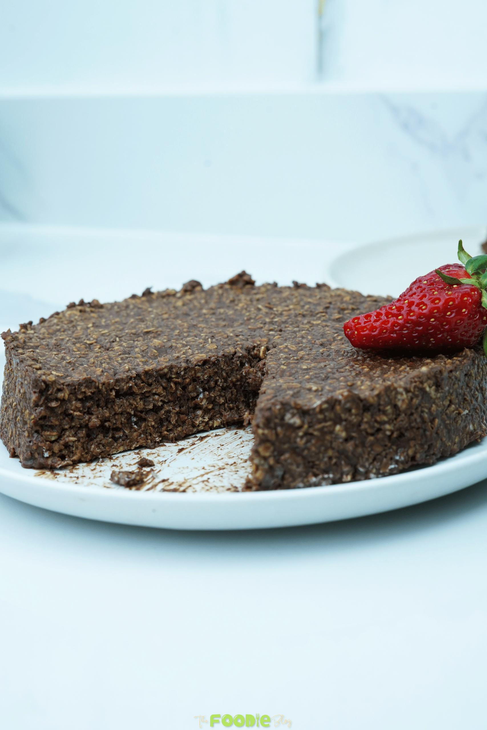 Chocolate oatmeal cake with a slice removed and a strawberry on top