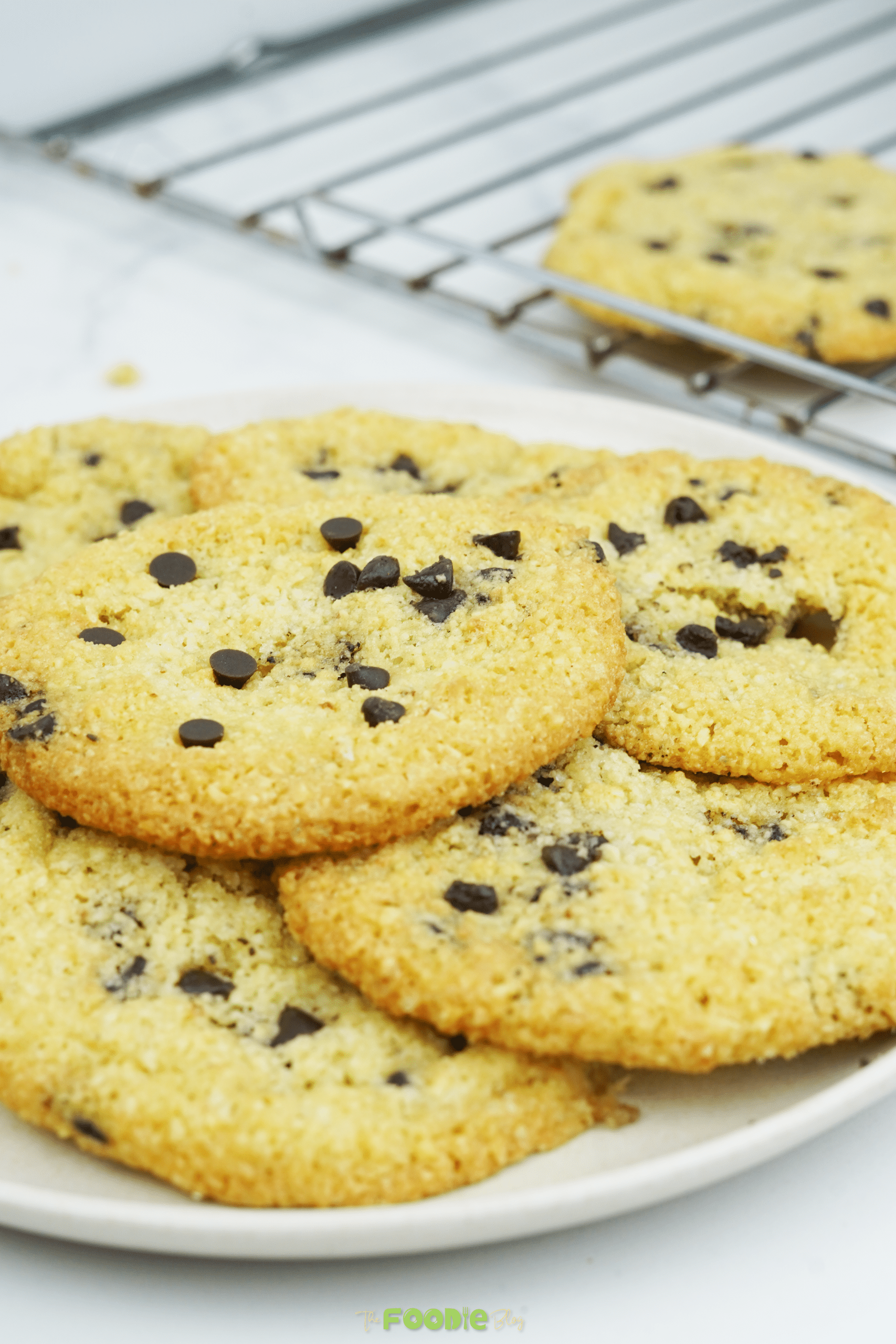 Almond flour chocolate chip cookies on a plate with a cooling rack in the background