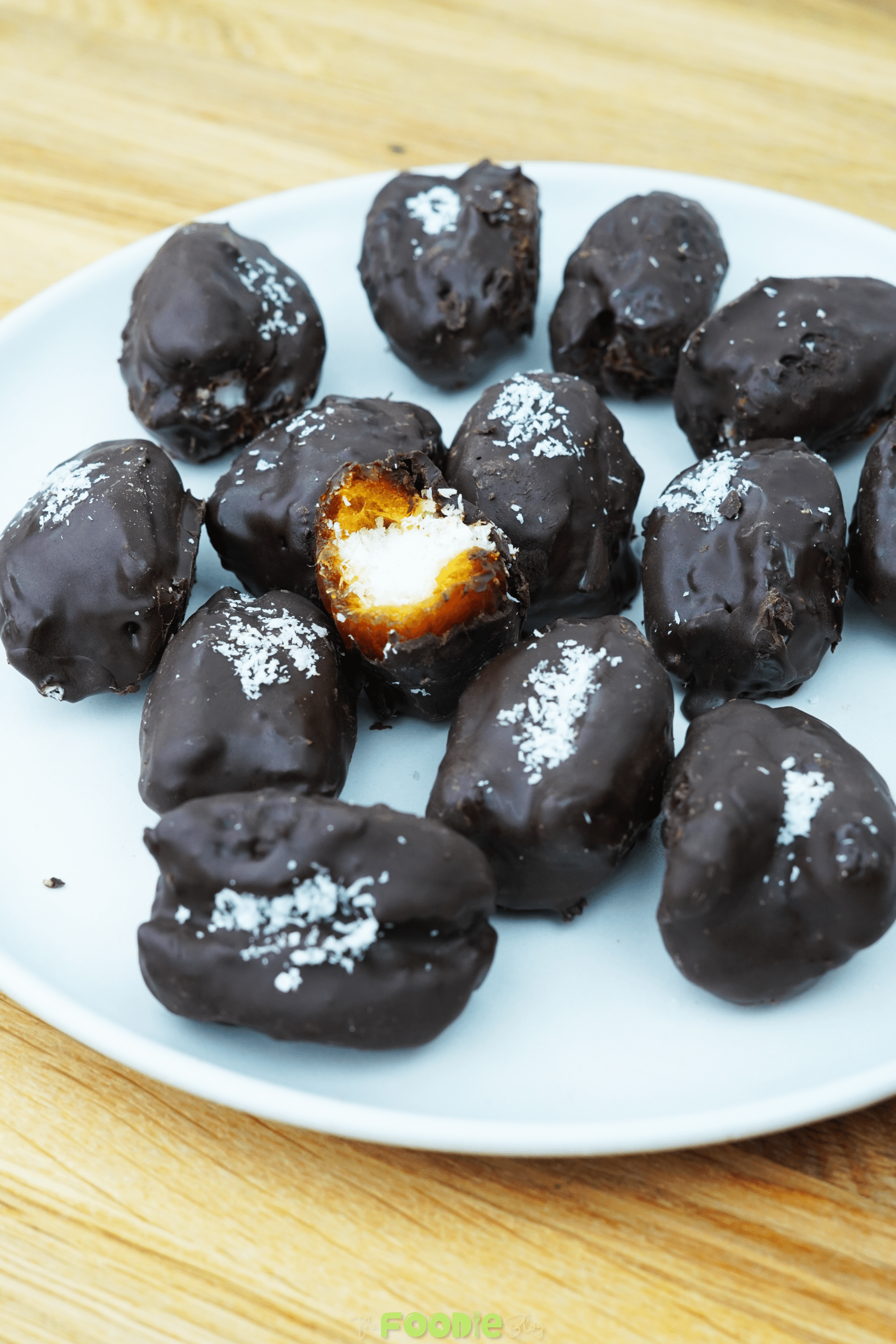 Close-up of chocolate-covered Bounty Dates with coconut filling visible in one bitten piece
