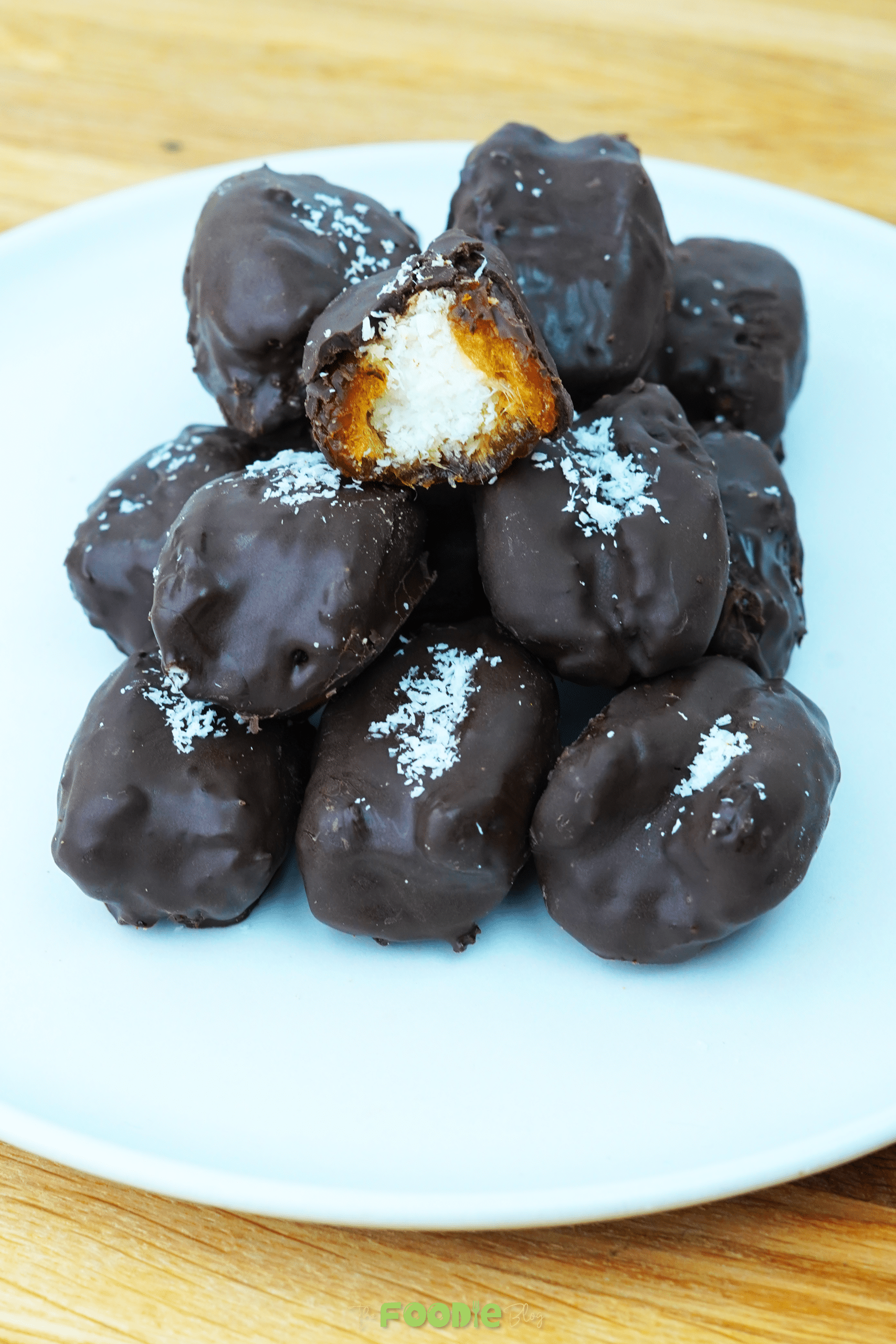 Pile of chocolate-covered coconut stuffed dates on a white plate