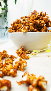 Bowl of caramel popcorn on a bright table with a soft, airy background