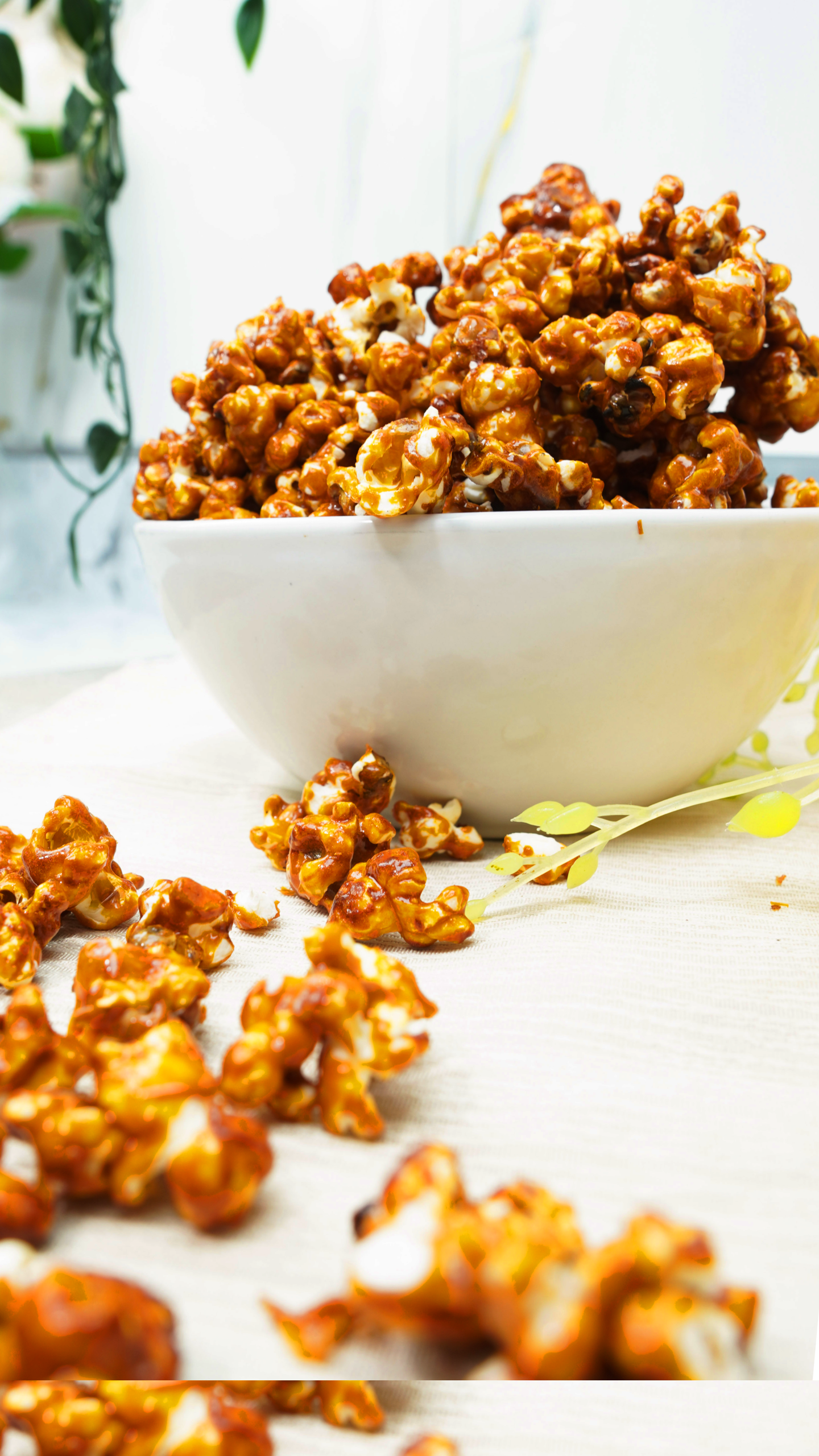 Bowl of caramel popcorn on a bright table with a soft, airy background