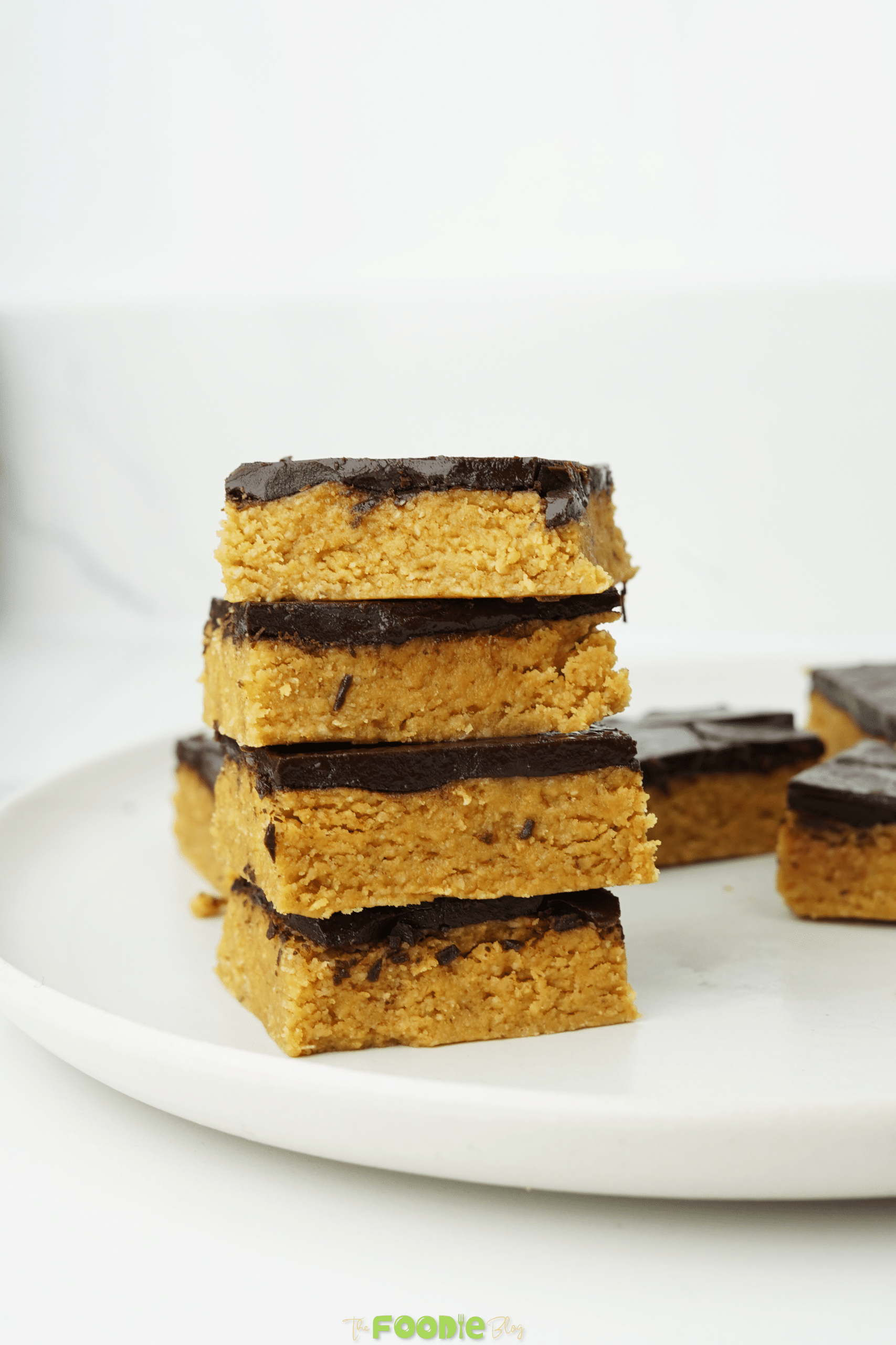 Chocolate peanut butter bars with a dark chocolate topping on a white plate