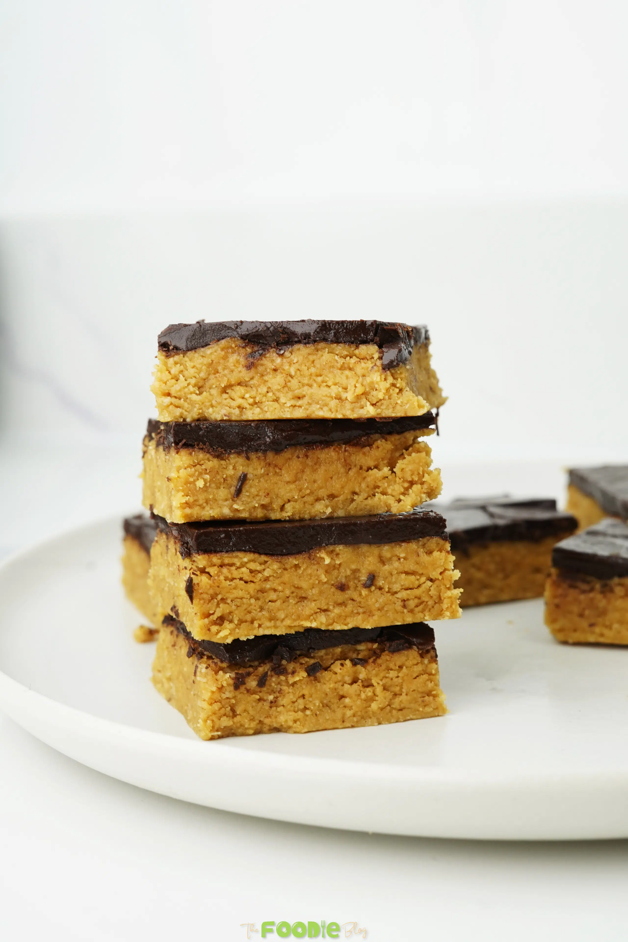 Chocolate peanut butter bars with a dark chocolate topping on a white plate