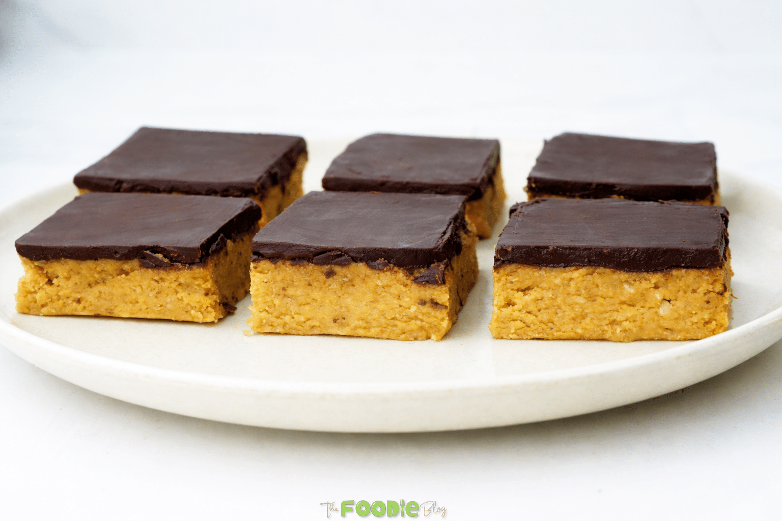 Chocolate peanut butter bars arranged on a plate with smooth chocolate tops