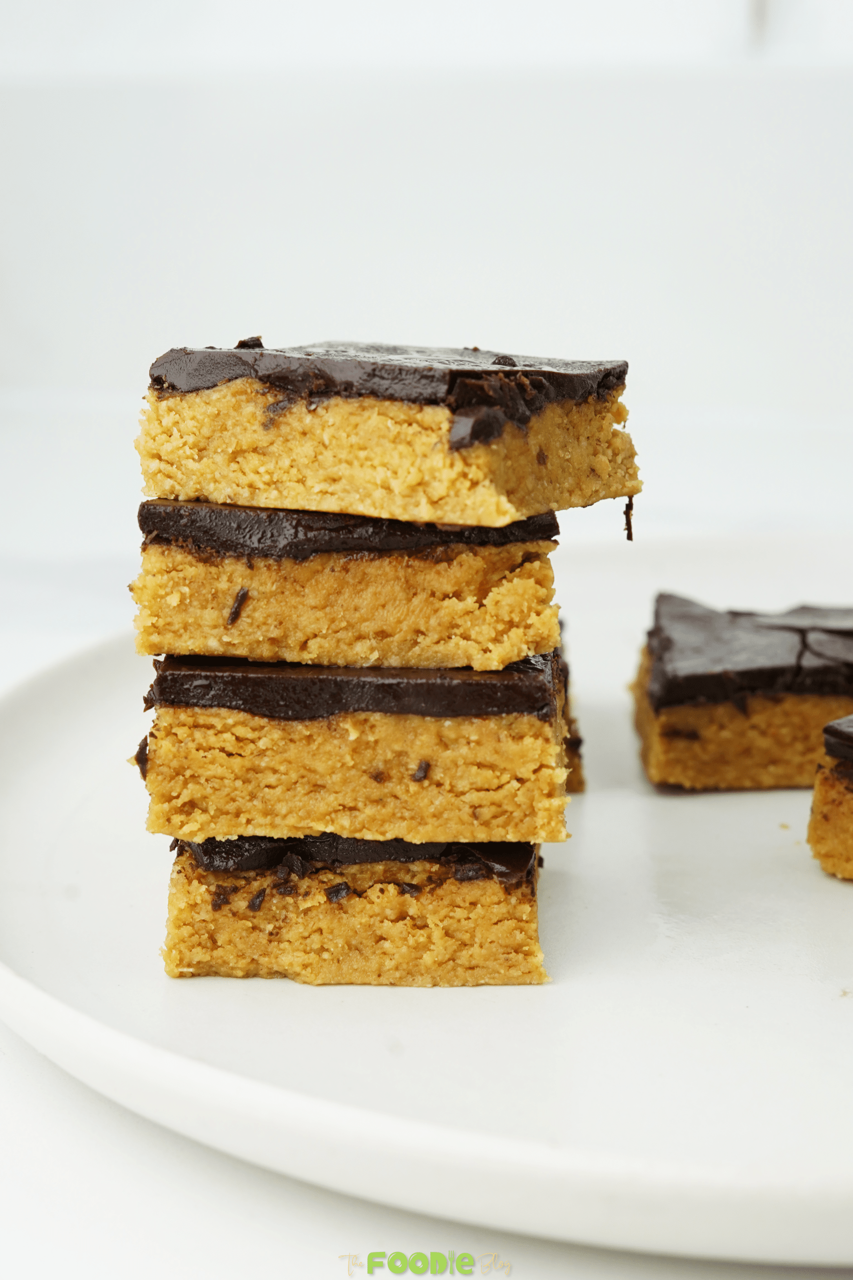 Stacked chocolate peanut butter bars showing the thick peanut butter layer and chocolate topping