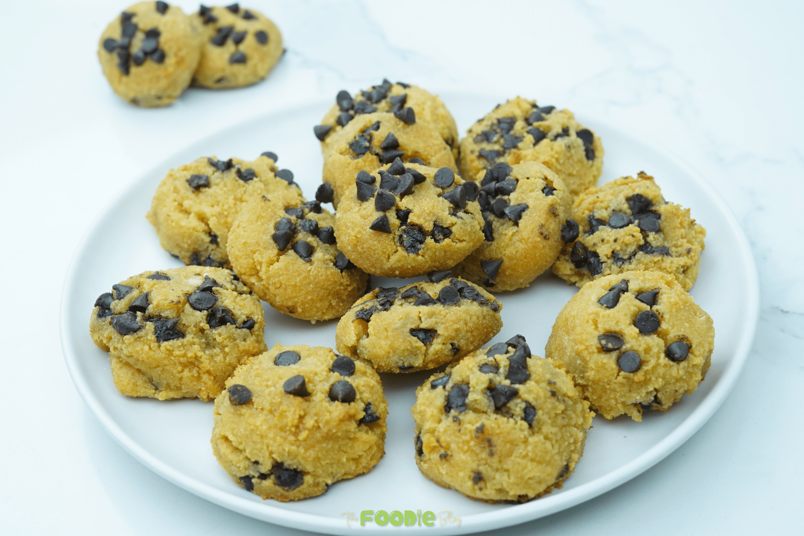 Wider view of stacked cottage cheese chocolate chip cookies on a white plate
