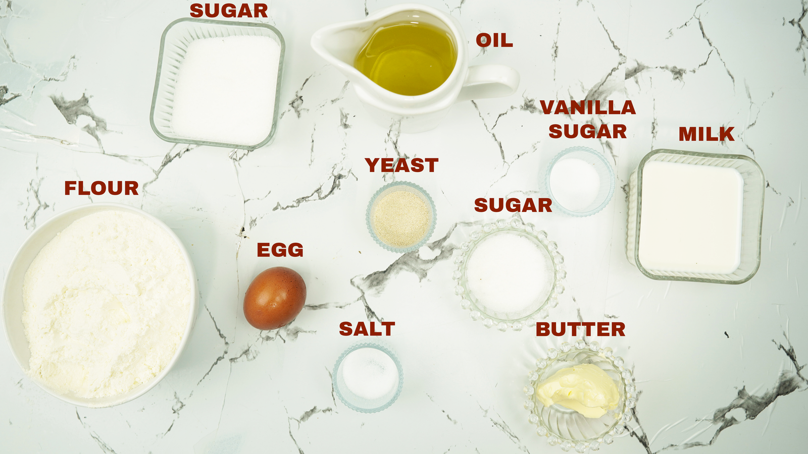 Flour, milk, sugar, yeast, egg, butter, oil, and salt arranged on a counter
