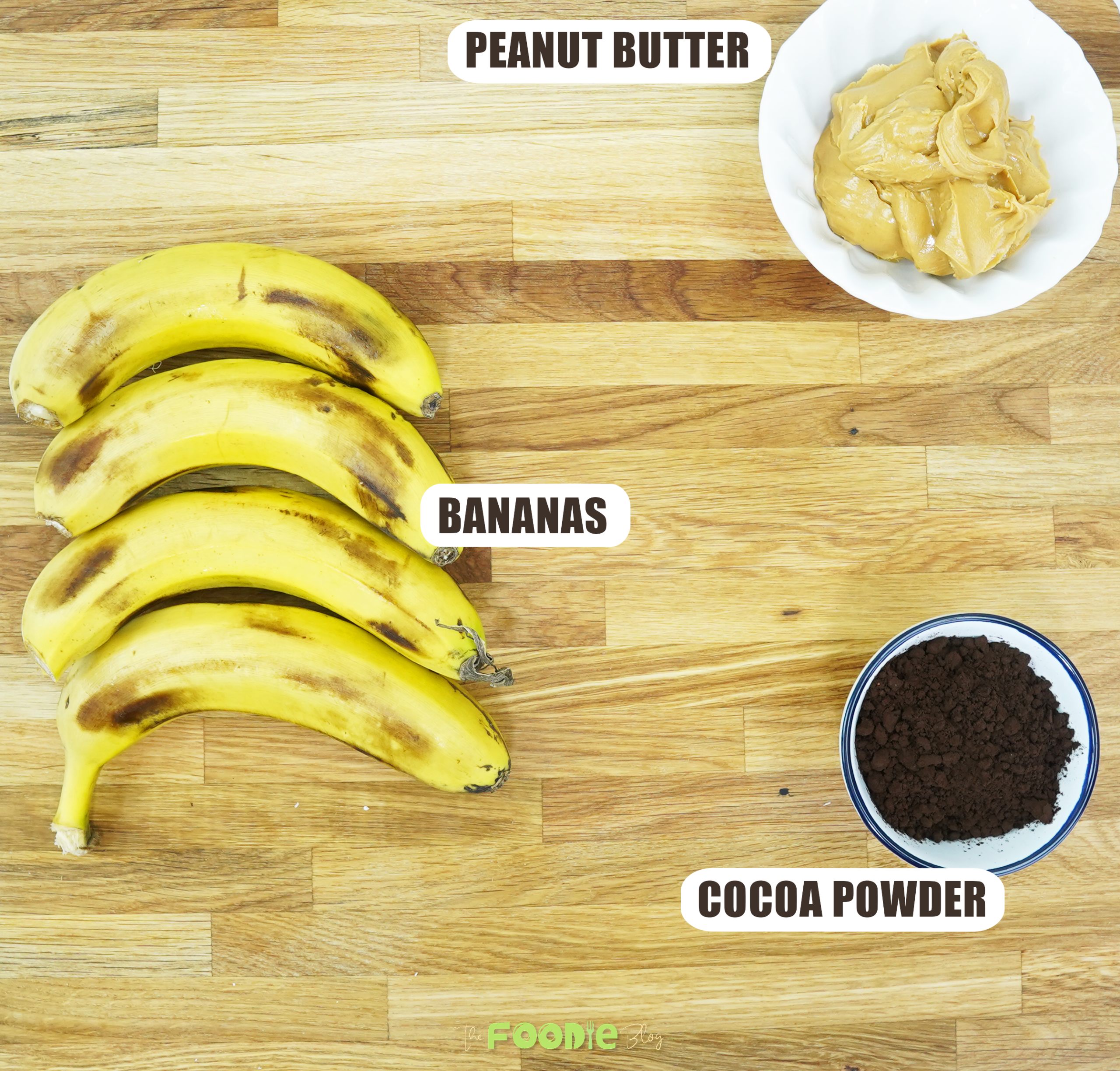 Bananas, peanut butter, and cocoa powder arranged on a wooden board