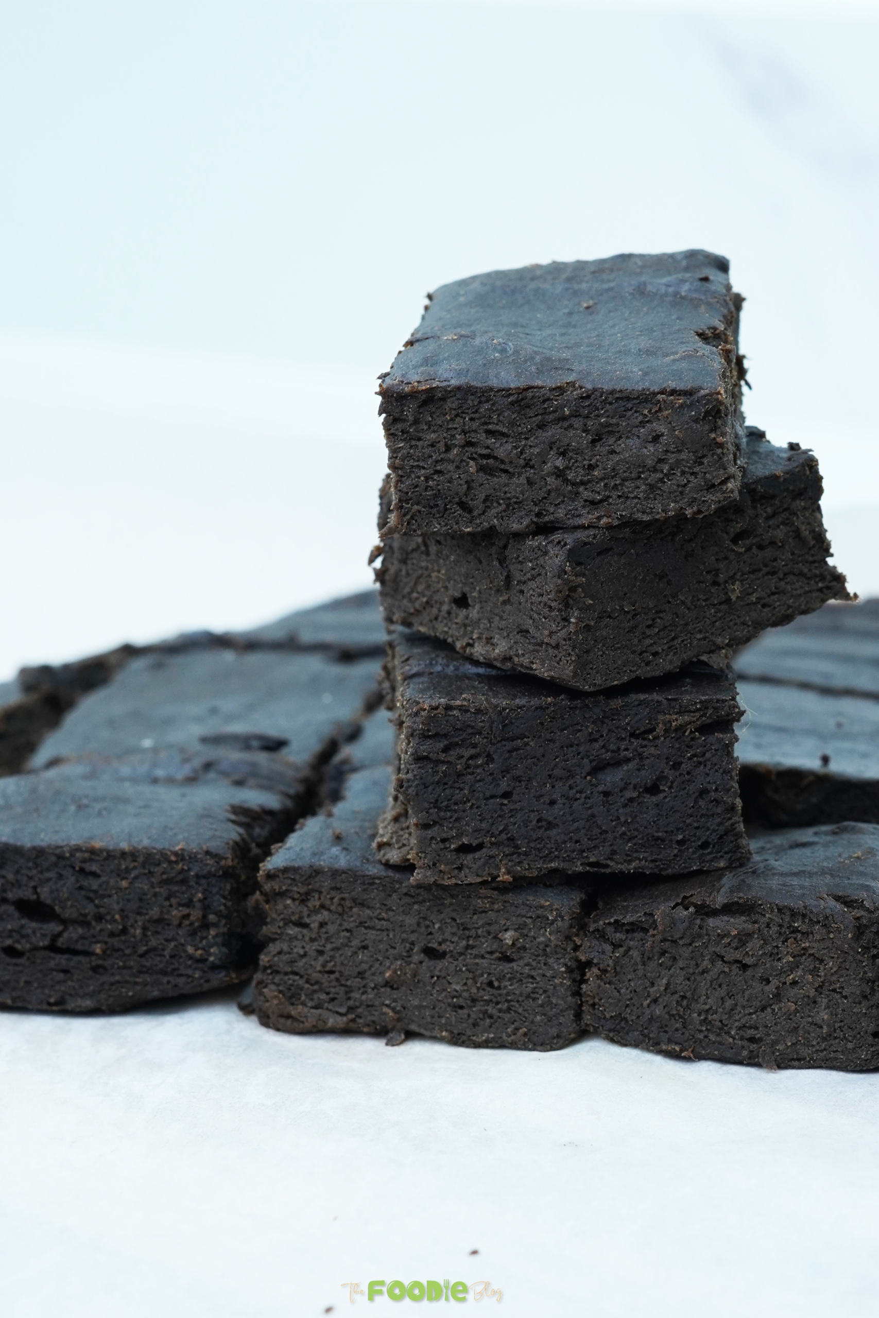 No-bake brownies cut into squares in a pan with one stack in front