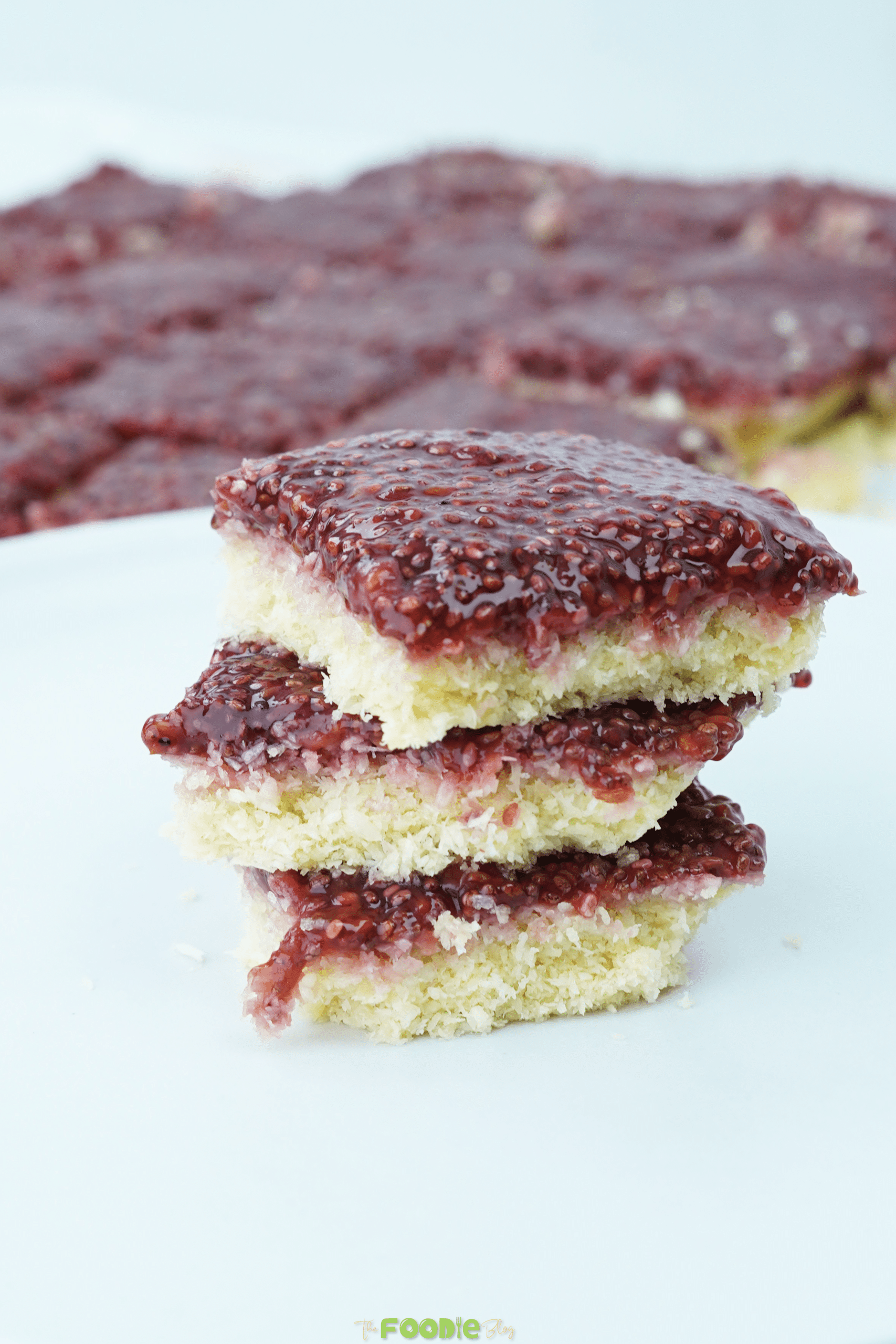 Close-up of coconut raspberry bars with glossy raspberry chia topping