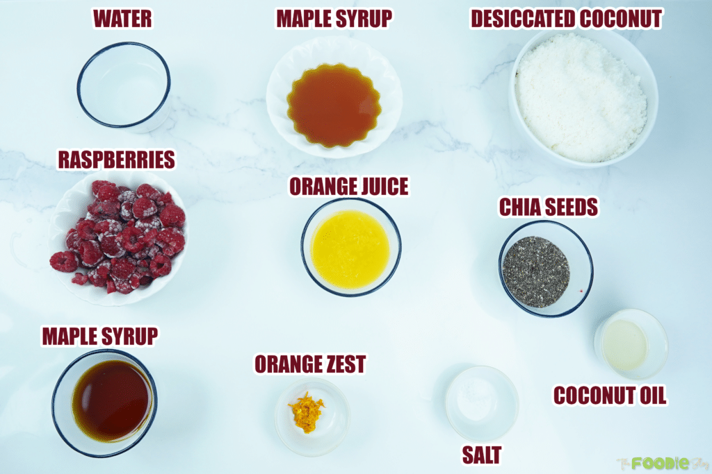Overhead view of ingredients for coconut raspberry bars including raspberries, coconut, chia, and orange