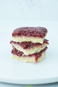 Stack of coconut raspberry bars showing the coconut layer and raspberry topping