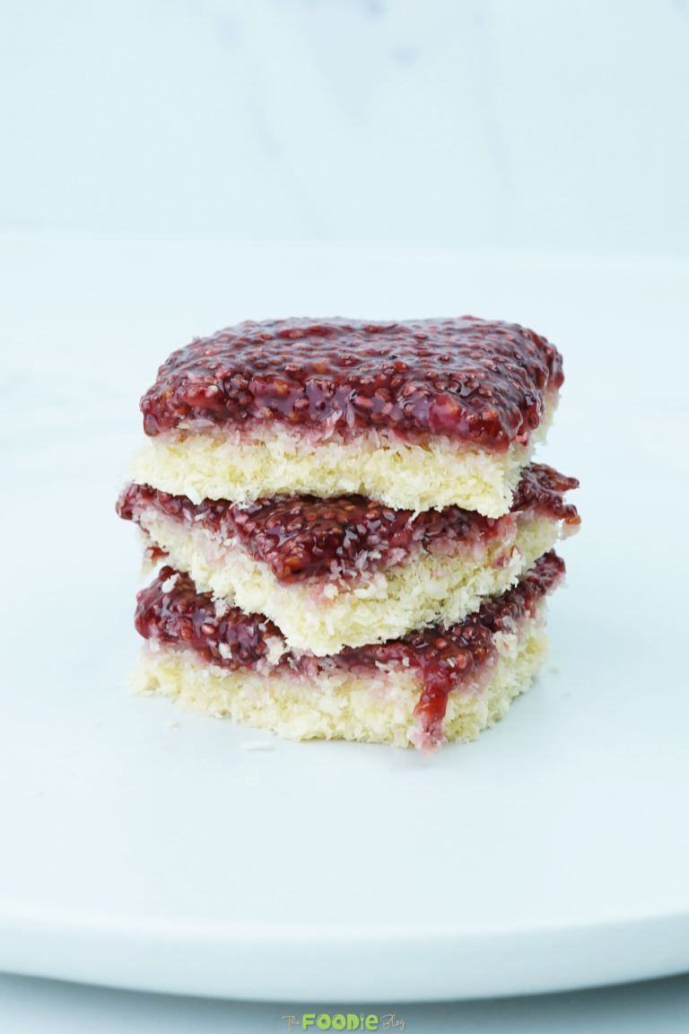 Stack of coconut raspberry bars showing the coconut layer and raspberry topping